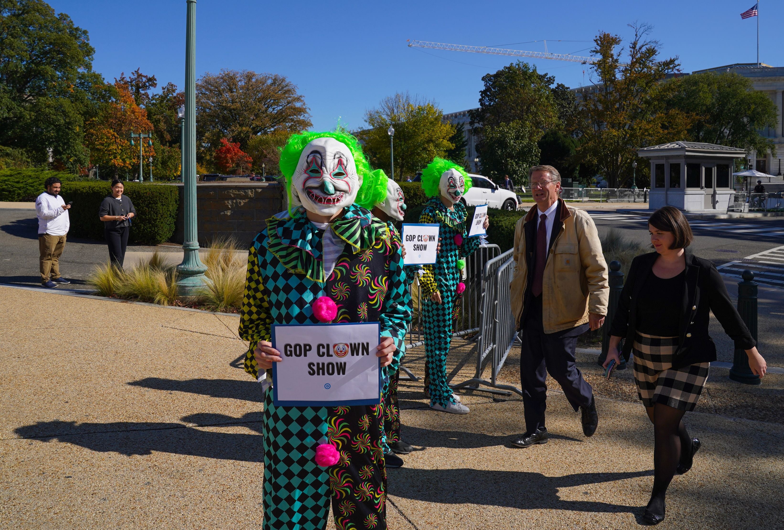 As Rep. Tim Burchett (R-TN) walks toward the U.S. Capitol while the House enters three weeks without a speaker, the Democratic National Committee holds a demonstration comparing the House Republicans' failure to elect a speaker to a "MAGA Clown Show" on Capitol Hill on October 24, 2023 in Washington, DC.