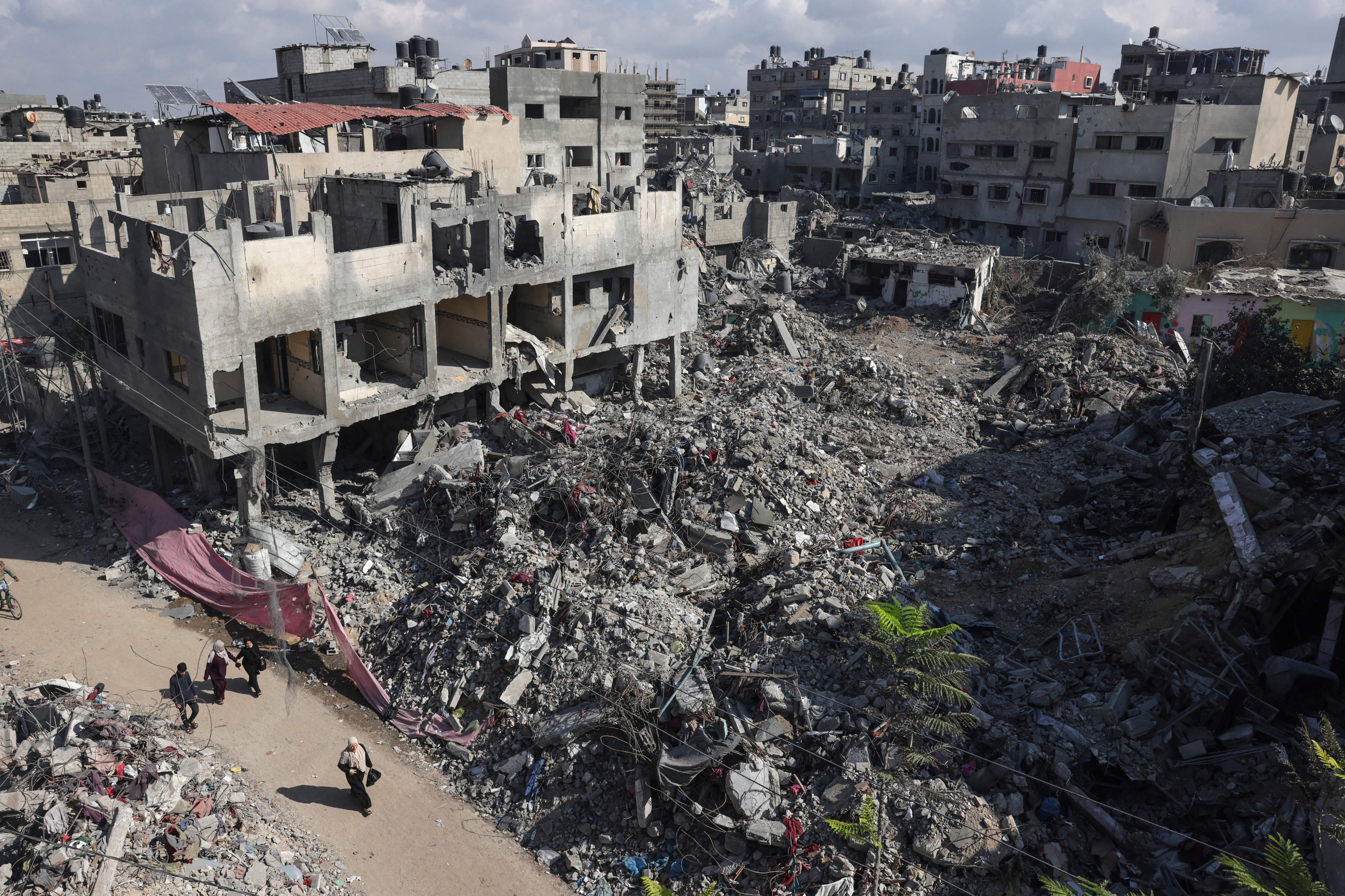 People walk past buildings destroyed following the Israeli bombardment of Bureij in the centre of Gaza Strip