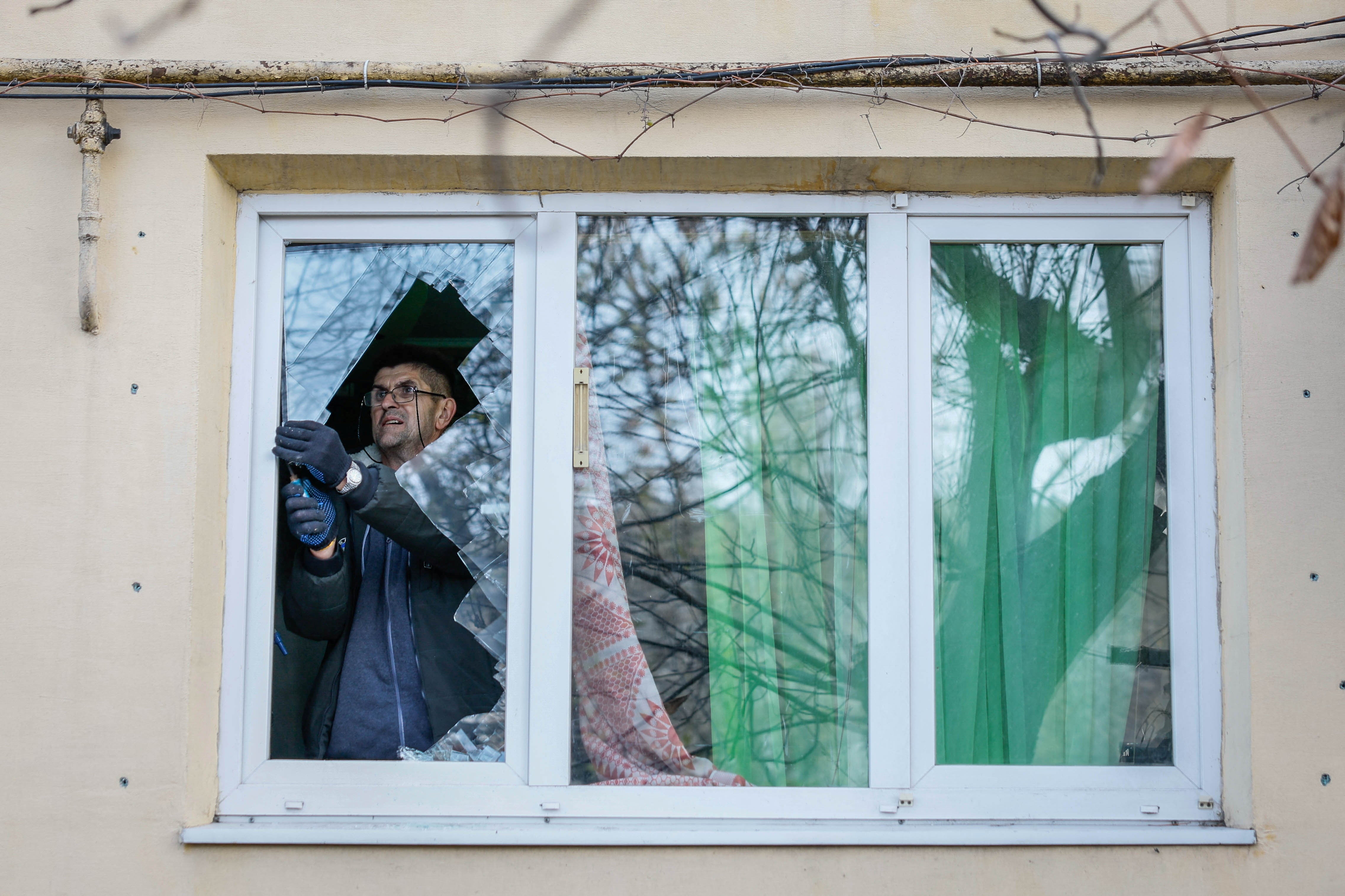 A resident removes broken glass from his window damaged by a Russian missile strike in Selydove, in Ukraine’s Donetsk region