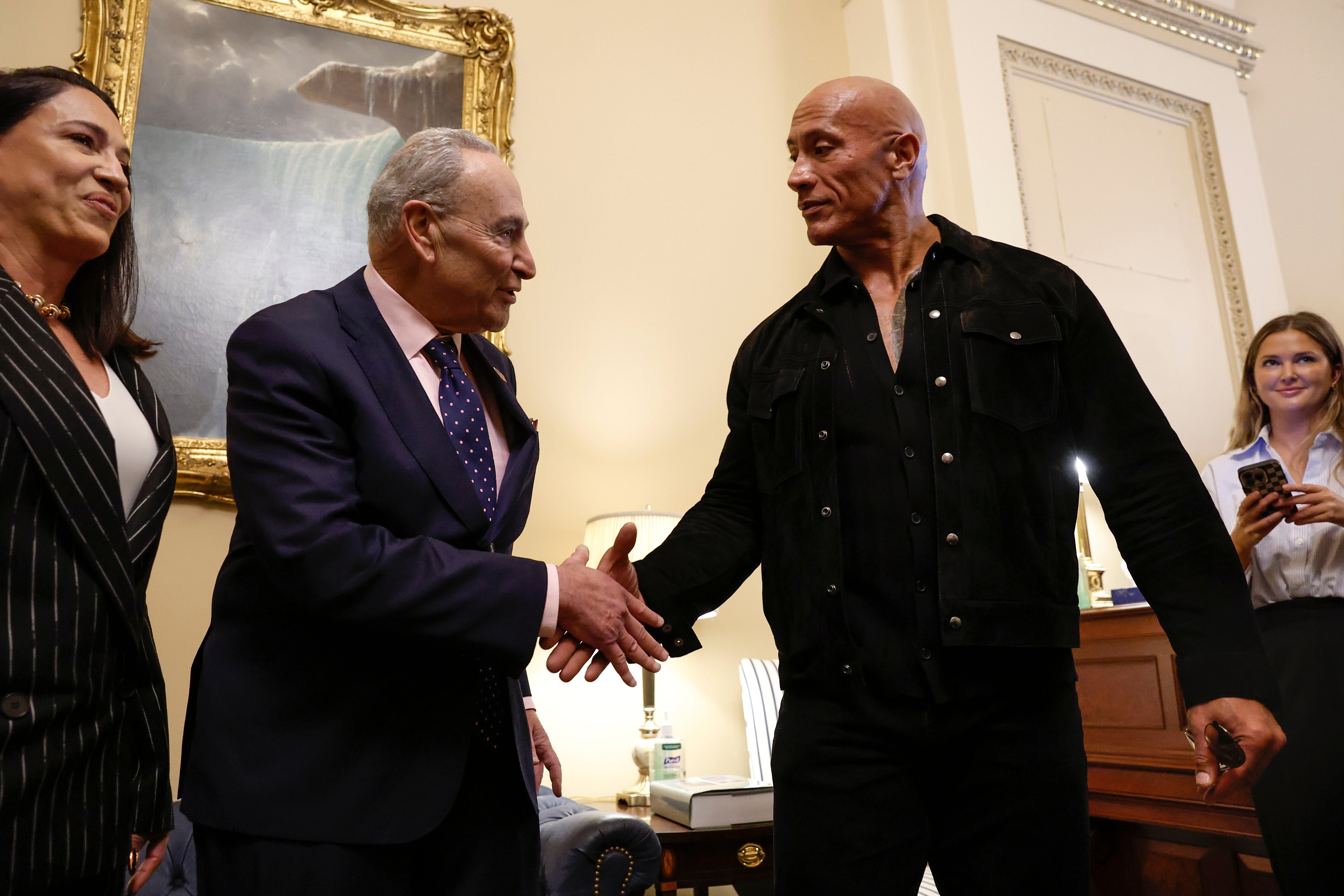 Dwayne Johnson shakes hands with U.S. Majority Leader Chuck Schumer at the Capitol Building on 15 November 2023
