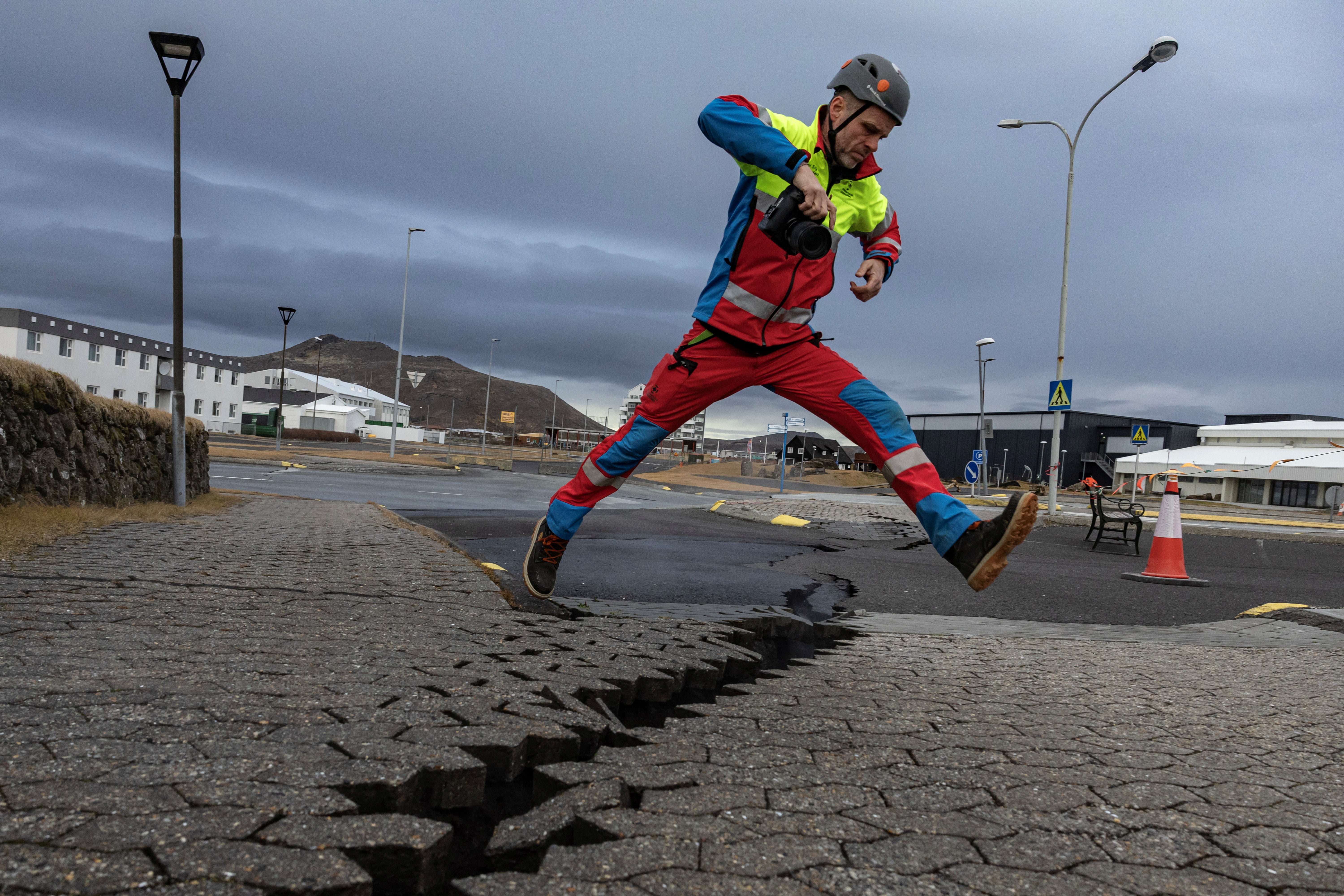 A member of search and rescue team jumps over the crack in a road in the fishing town of Grindavik