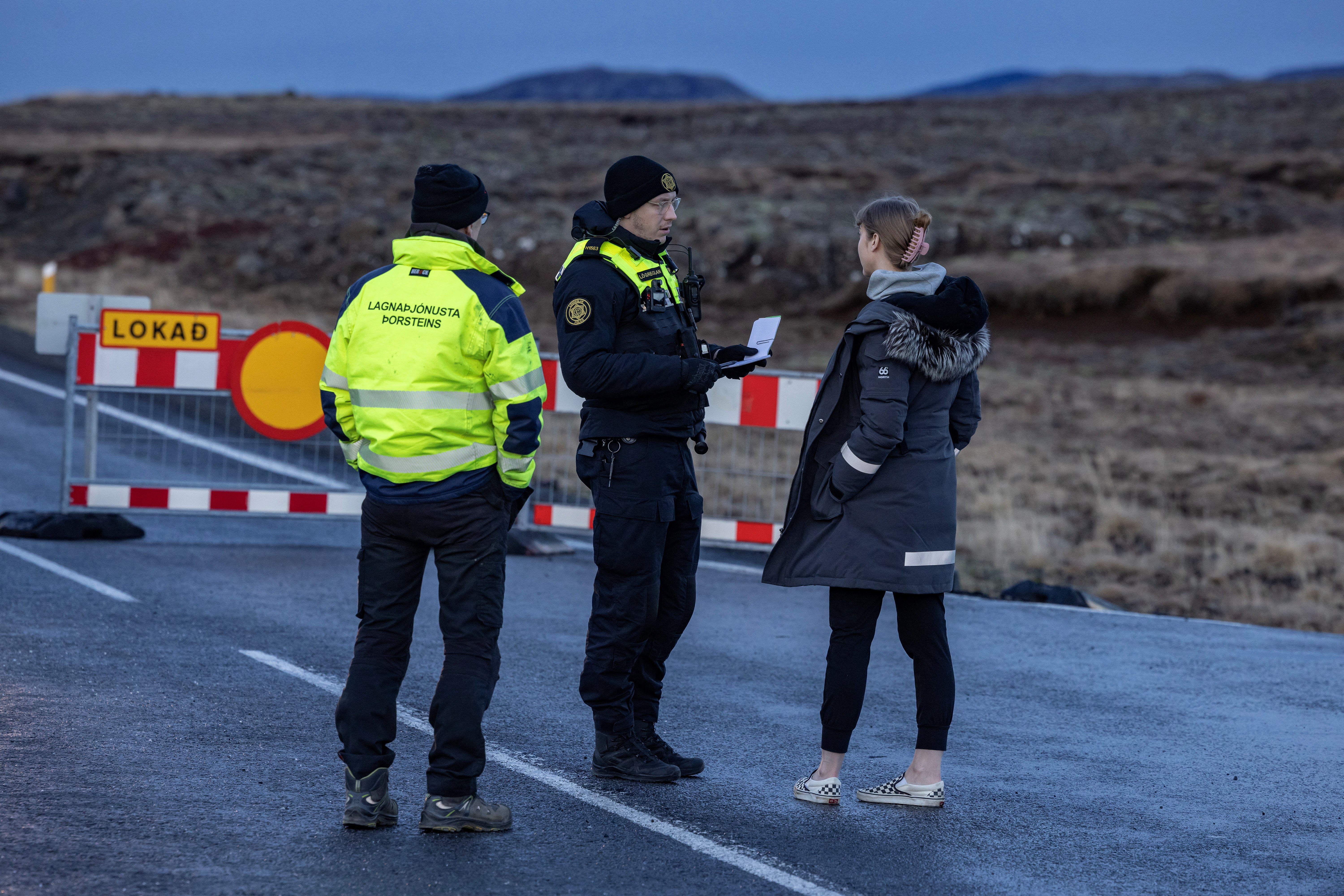 <p>A police officer talks to a local resident on a road leading to the fishing town of Grindavik</p>