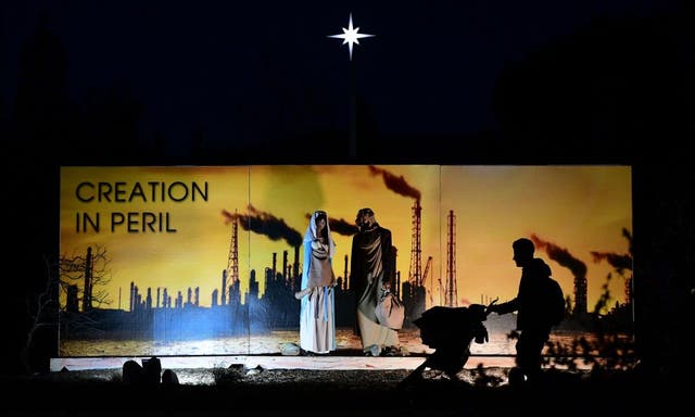 <p>A man pushes a baby in a stroller past the Nativity Scene at Claremont United Methodist Church, showing the Holy Family in an industrial scene with smoke, pollution and a scorched earth to call attention to to the dangers of environmental pollution and climate change in Claremont, California</p>