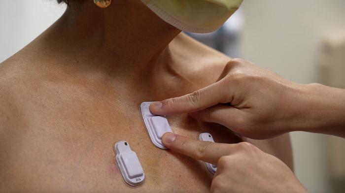 A health care worker places the wearable devices across a patient's chest to capture sounds throughout the lungs that are associated with breathing
