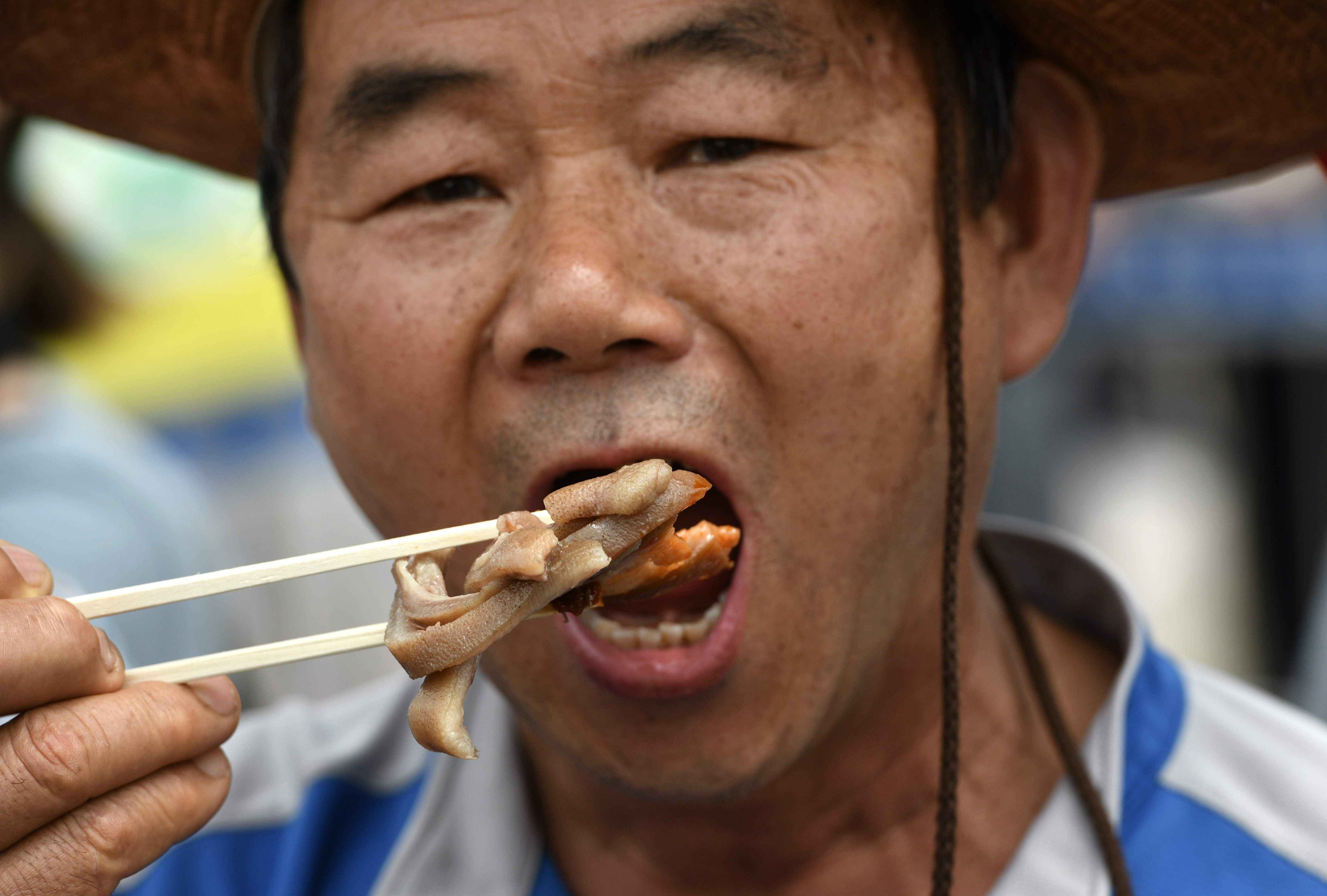 File: A South Korean dog farmer eats dog meat during a counter-rally against animal rights activists demonstrating against the meat’s trade in 2019