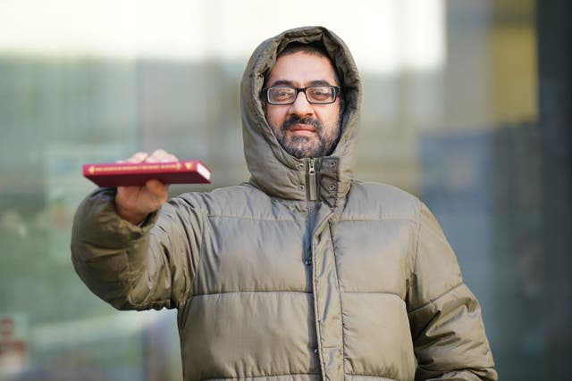 Urslaan Khan holds up a copy of The Genius of Dickens by Professor Michael Slater as he leaves Westminster Magistrates’ Court (Lucy North/PA)