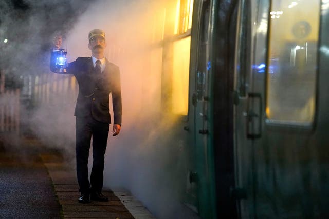 <p>An actor playing the role of the Conductor, poses for a photograph alongside the Polar Express Train Ride at the Swanage Railway in Dorset. </p>