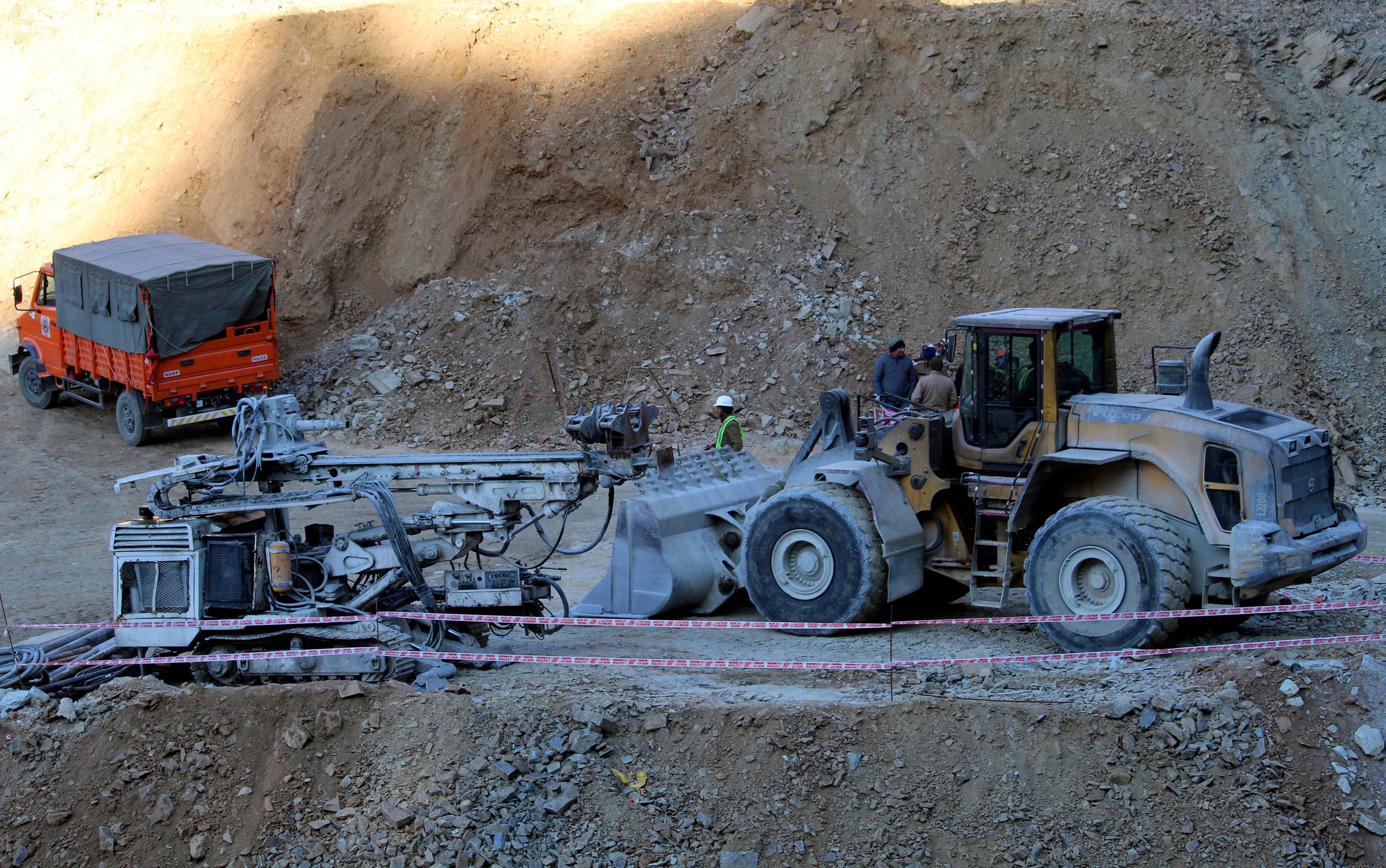 Heavy machinery stand near the entrance to the site of an under-construction road tunnel that collapsed in mountainous Uttarakhand state