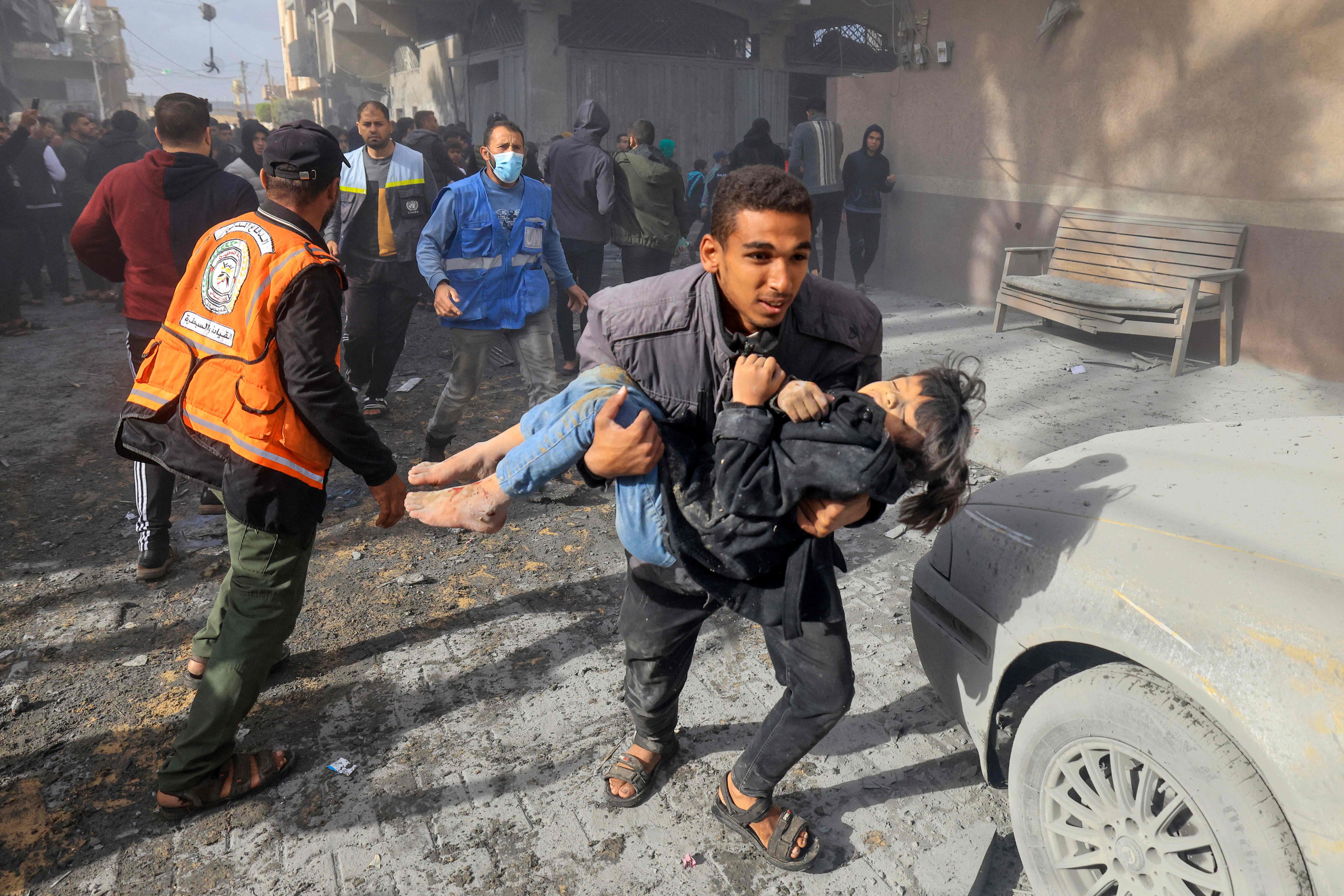 A man carries a child injured in an Israeli strike on Rafah in the southern Gaza Strip on November 20, 2023