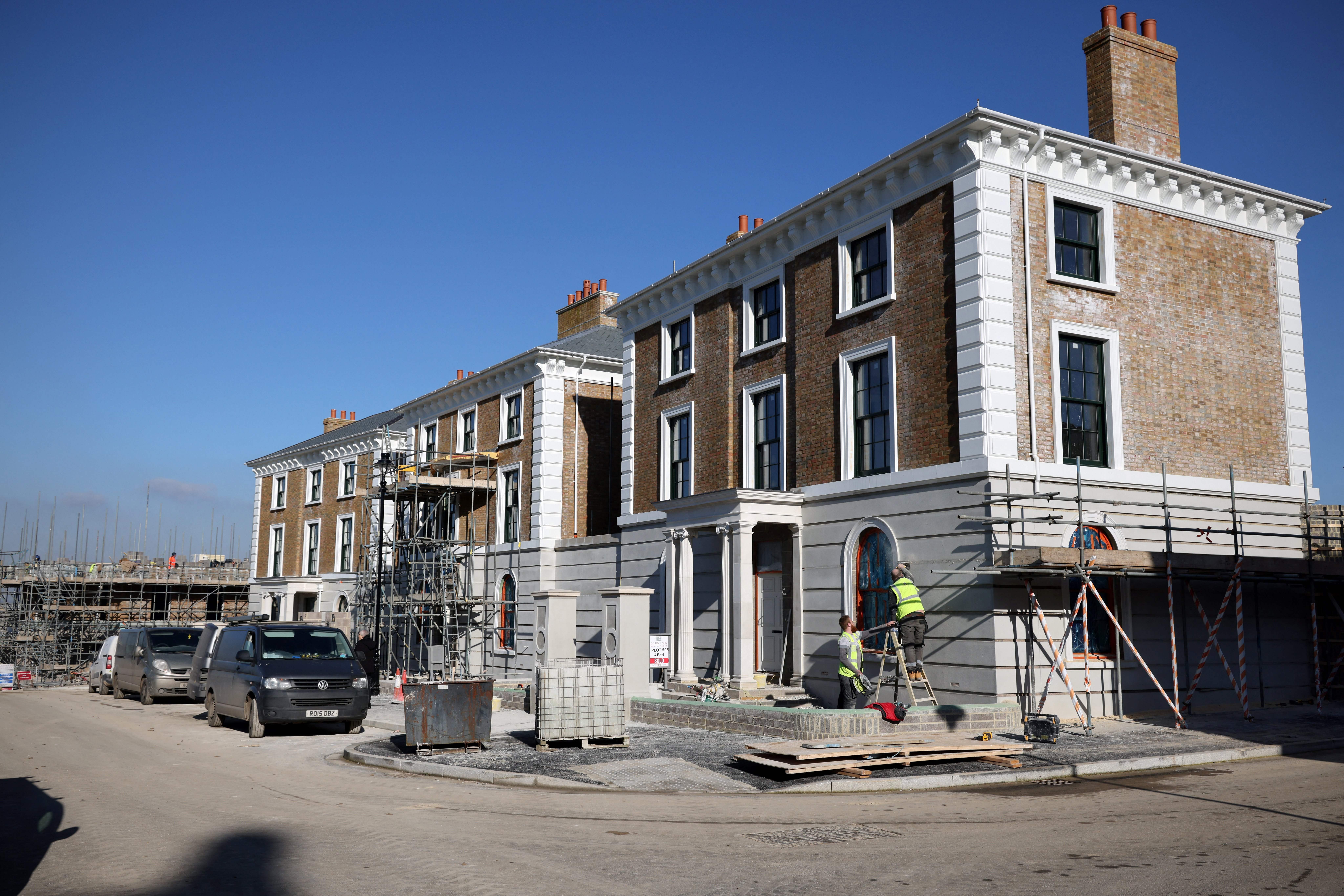 Construction builders work on the facade of a newly built house in the latest phase of development in Poundbury