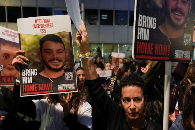 <p>Niva Wenkert, the mother of 22-year-old Israeli hostage Omer Wenker, holds placards featuring her son’s face at a rally in Tel Aviv on Monday</p>