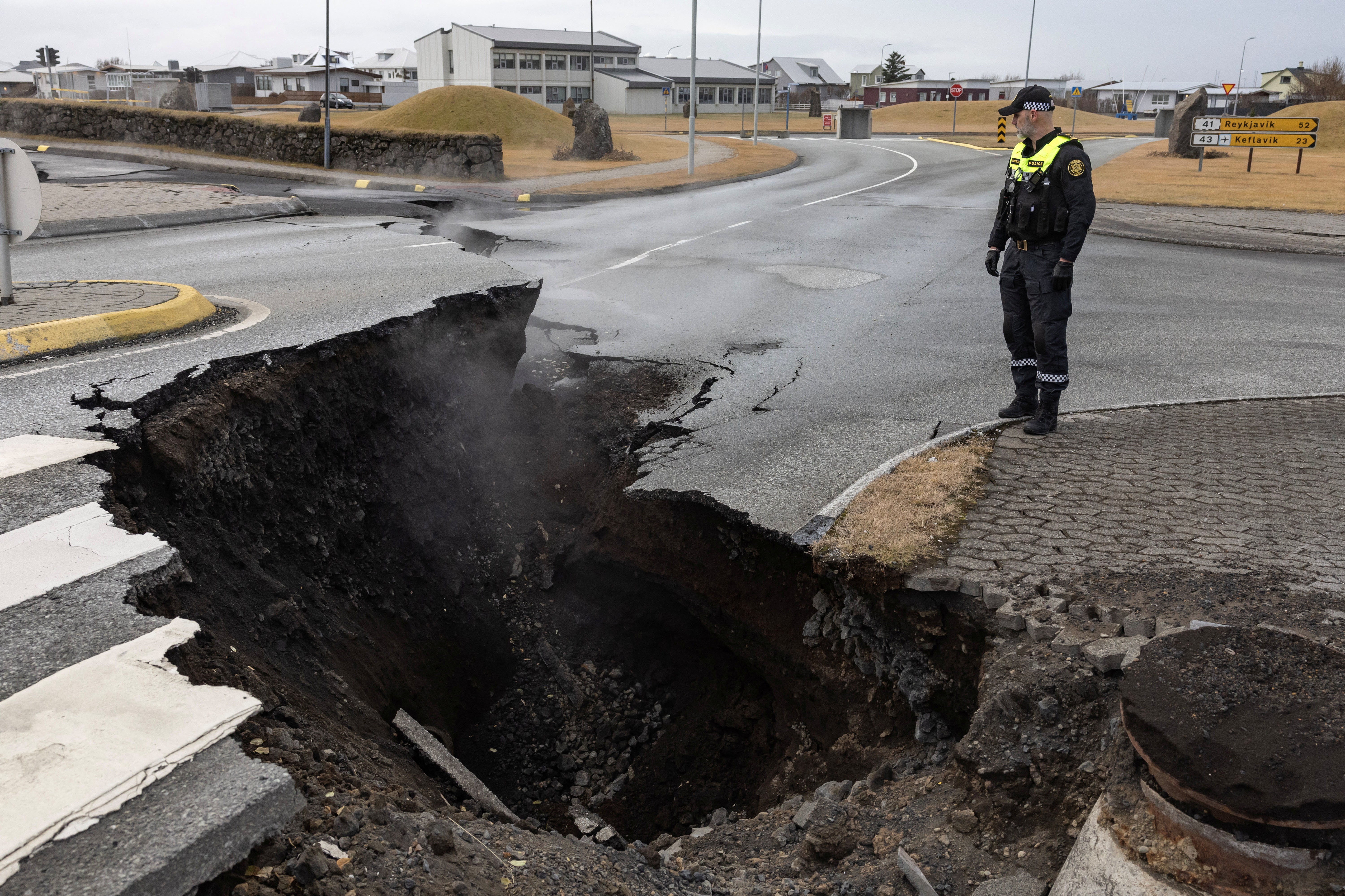 <p>A police officer stands by the crack in a road in the fishing town of Grindavik</p>