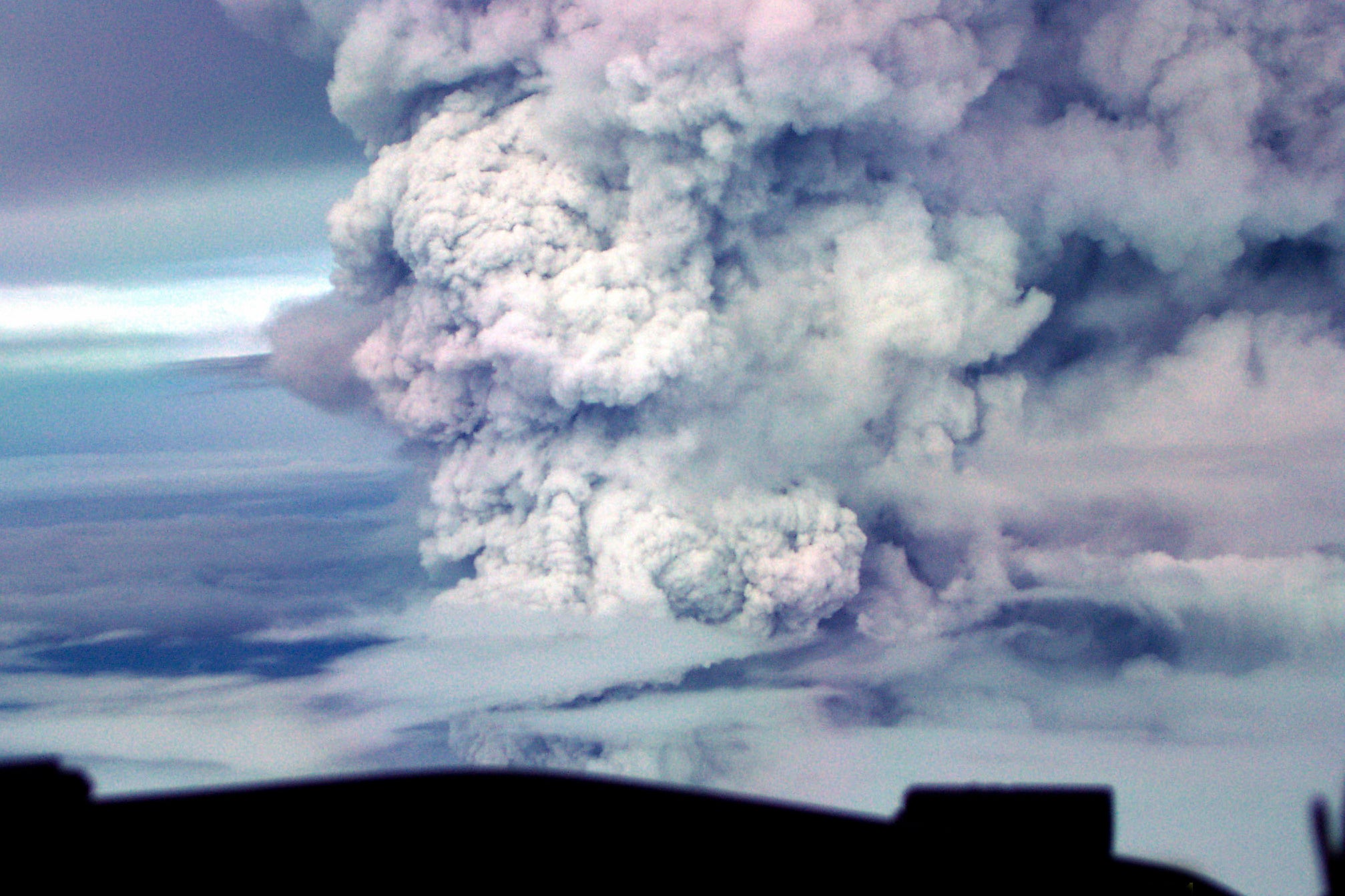Mount Ulawun erupting, sending plumes of smoke and ash high into the sky.