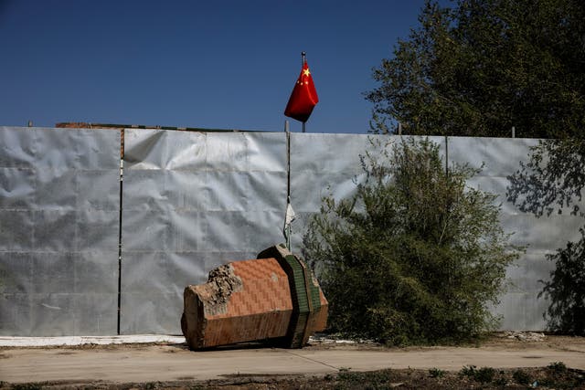 <p>A part of a minaret broken off from the former Xinqu Mosque lies near a Chinese national flag in a yard adjacent to the former house of worship in Changji</p>