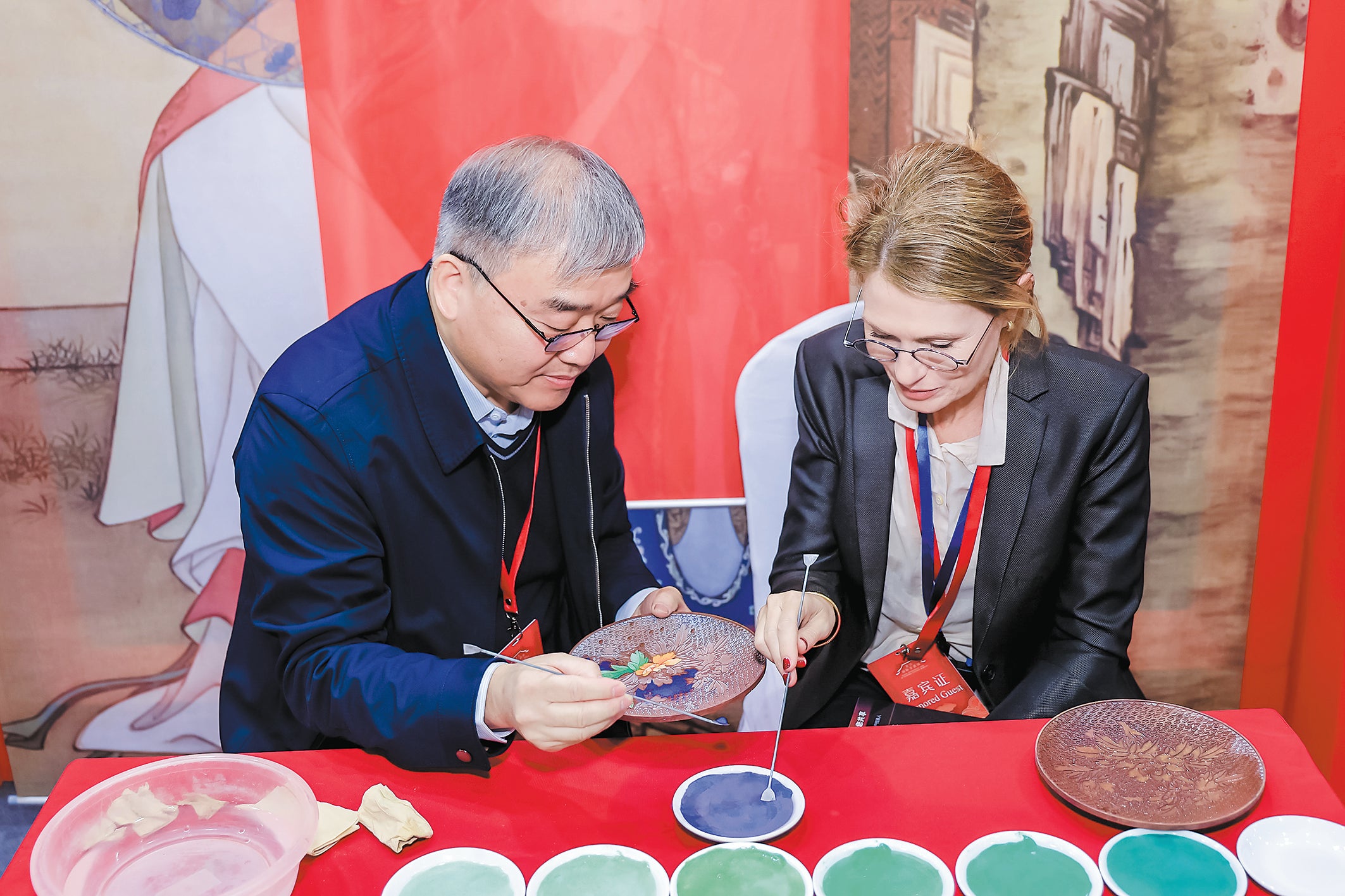 An artist demonstrates cloisonne making to a visitor at the event