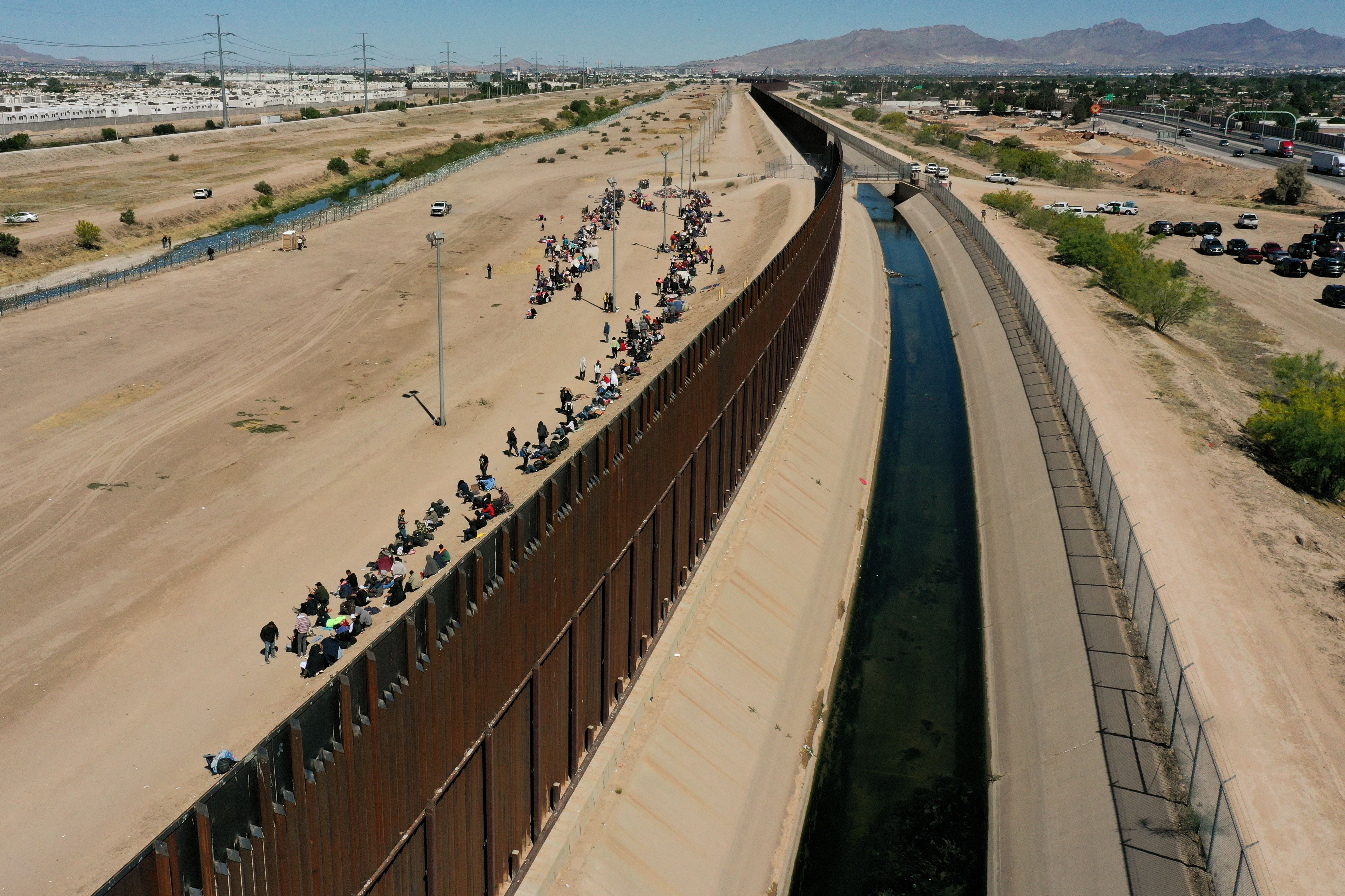 An aerial image shows migrants waiting along the border wall to surrender to US Customs and Border Protection (CBP) Border Patrol agents for immigration and asylum claim processing after crossing the Rio Grande river into the United Staes on the US-Mexico border in El Paso, Texas, on May 10, 2023
