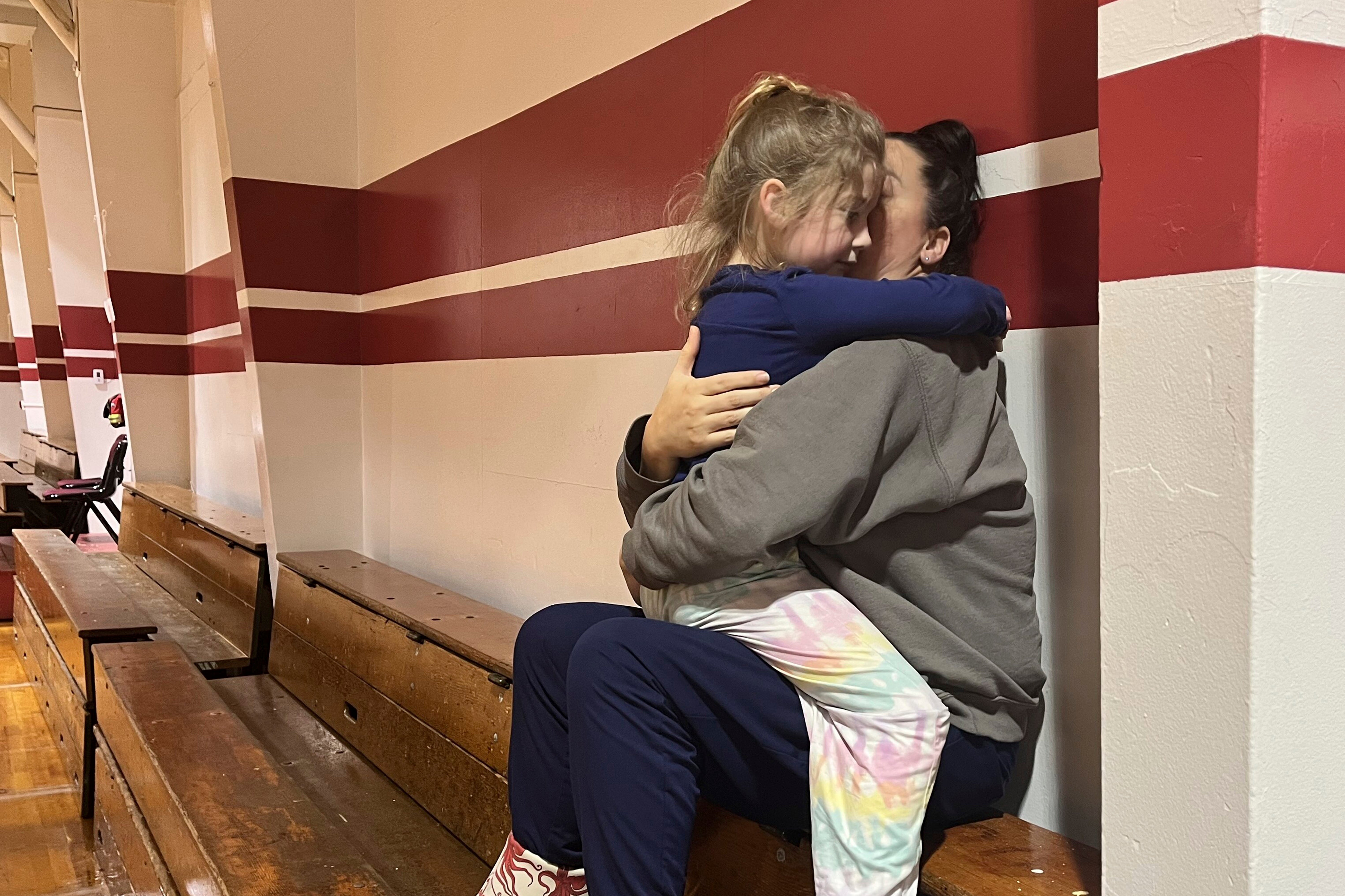 Angela Stires is embraced by her daughter, Tuesday, 21 November 2023, at the community center, which opened for people displaced by the landslide in Wrangell, Alaska