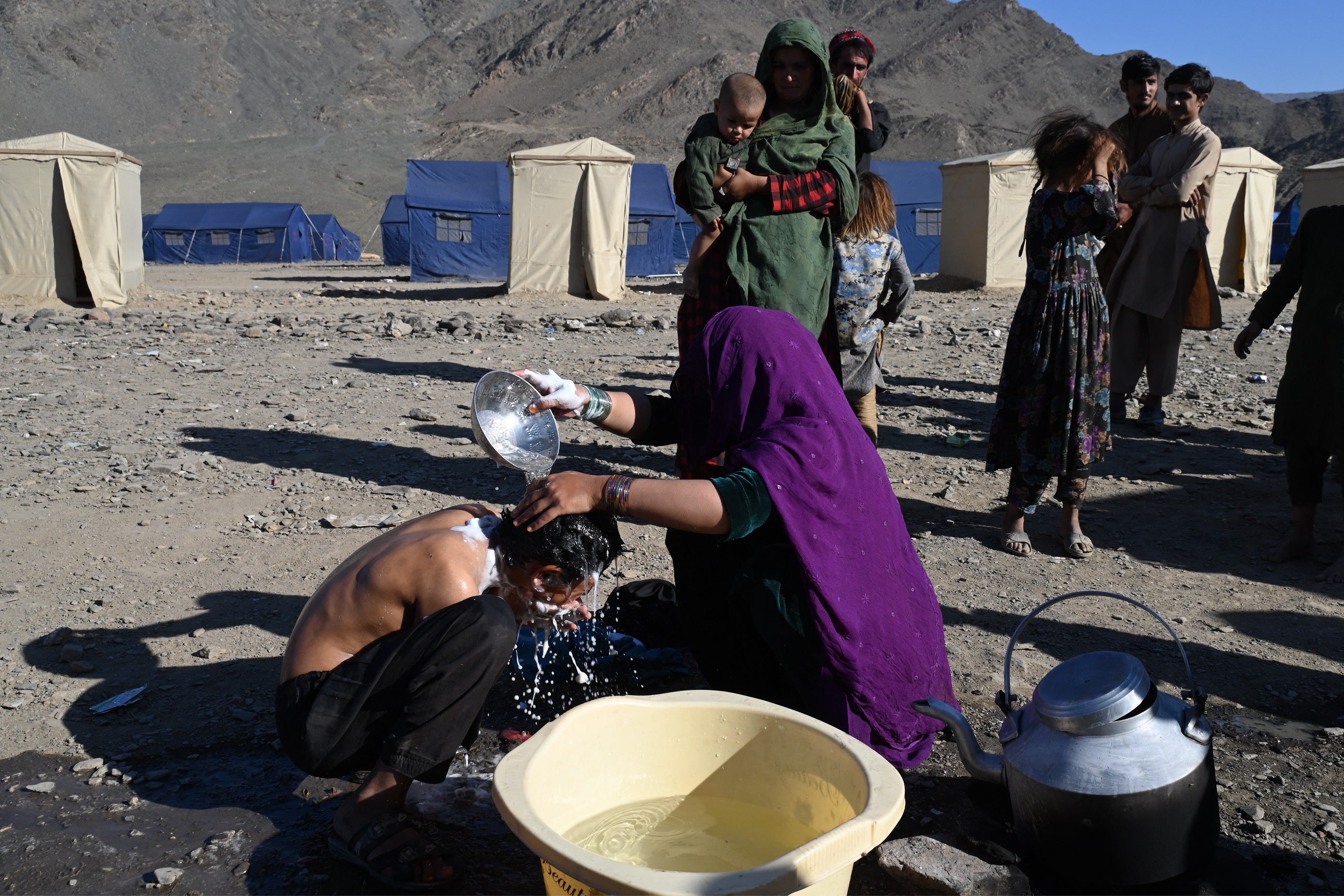 An Afghan refugee woman bathes her brother