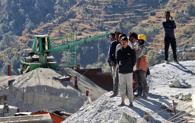 <p>People watch rescue operations at the site of an under-construction road tunnel that collapsed trapping 41 workers in Silkyara in the northern Indian state of Uttarakhand, Wednesday, 22 November 2023</p>