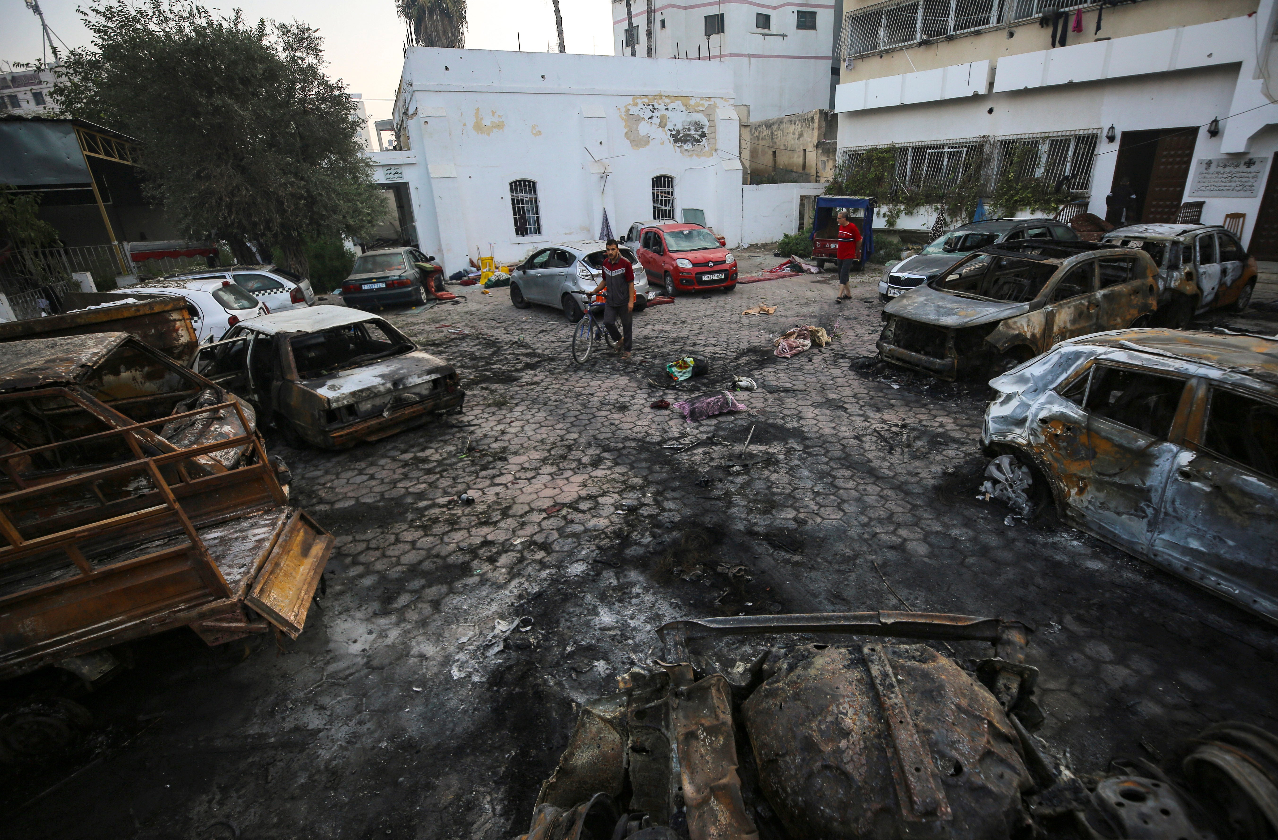 Men look over the site of a deadly explosion at al-Ahli Hospital in Gaza City