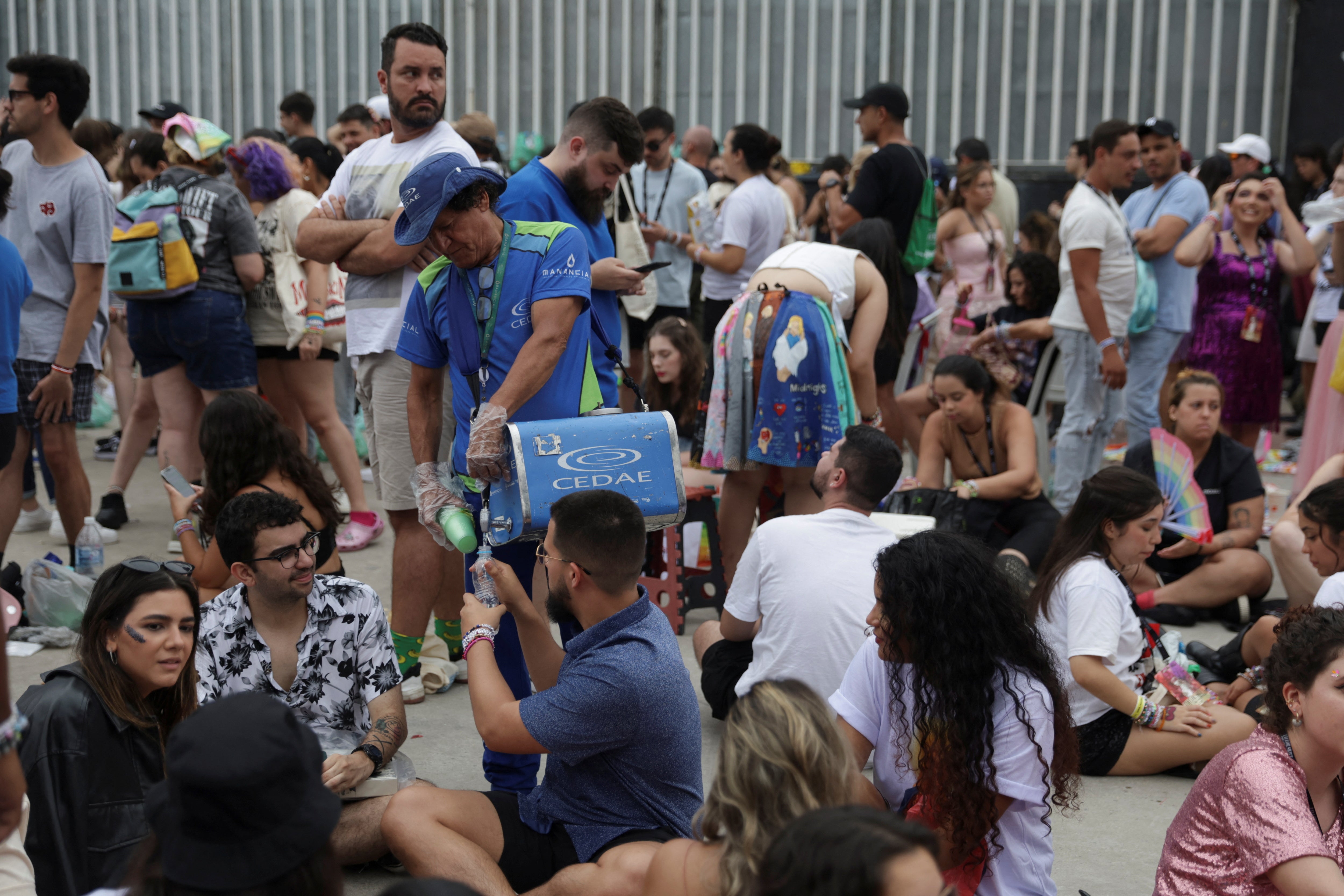 A worker distributes water to fans in Rio de Janeiro waiting for Ms Swift’s Eras Tour on 20 November