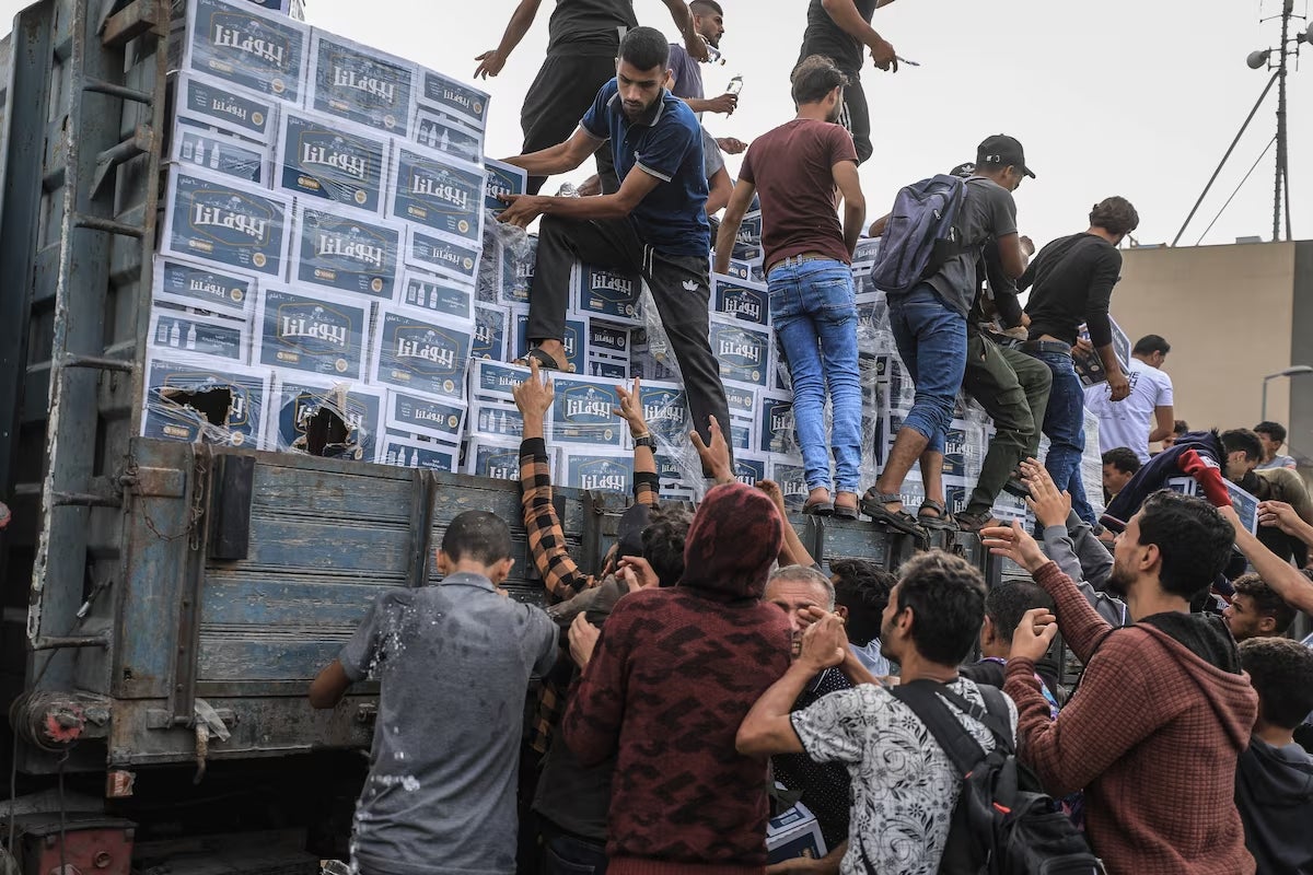 Displaced Palestinians receive bottled water amid a shortage of drinkable water in the Gaza Valle