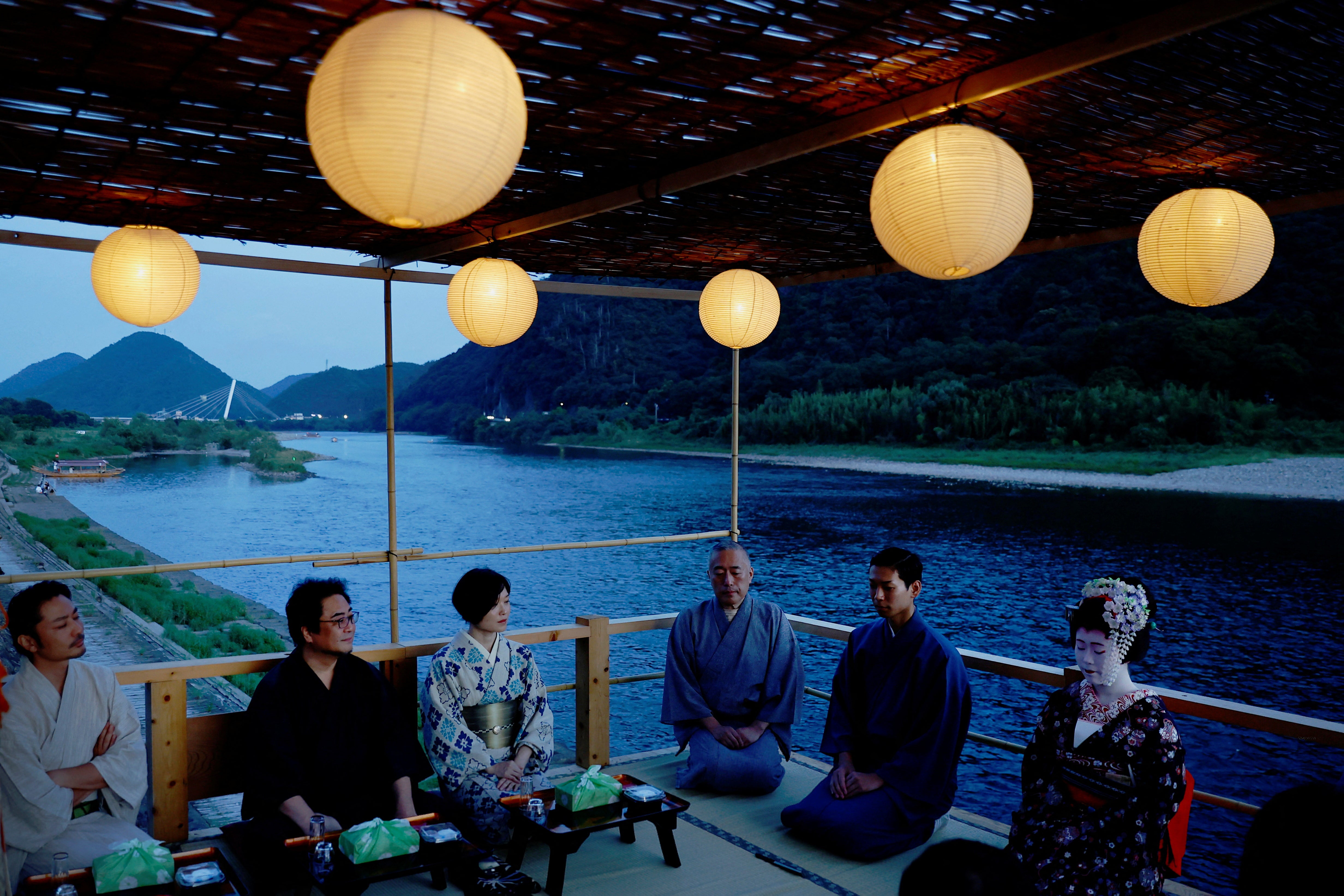 Houkan (male counterpart to Geisha) Tatsuji, 29, and Maiko (apprentice female Geisha), Kikuyu, 20, sit with visitors to watch ‘ukai’ at a riverside observation deck in the Nagara River