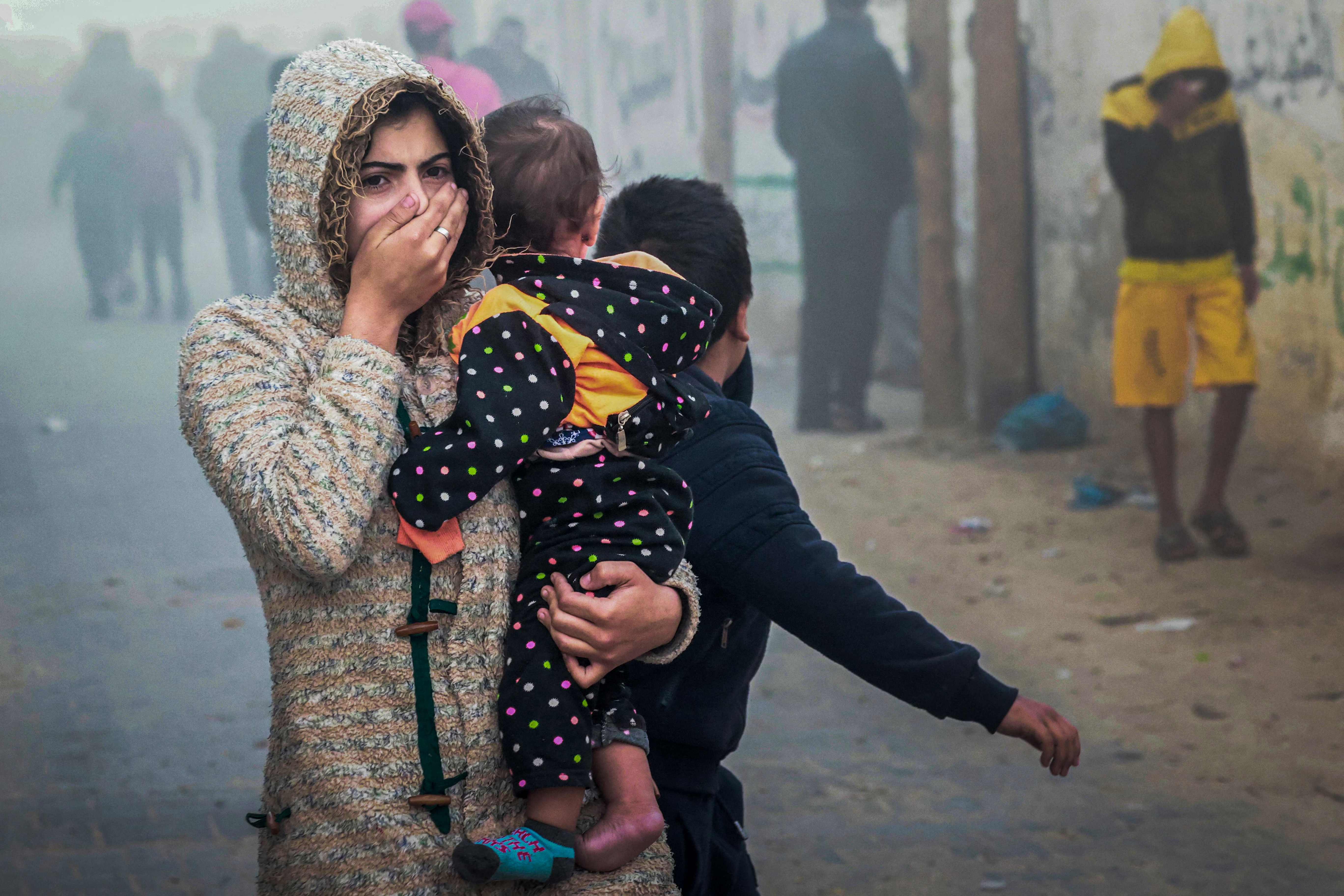 A woman and child flee an Israeli strike in Rafah in southern Gaza on Thursday