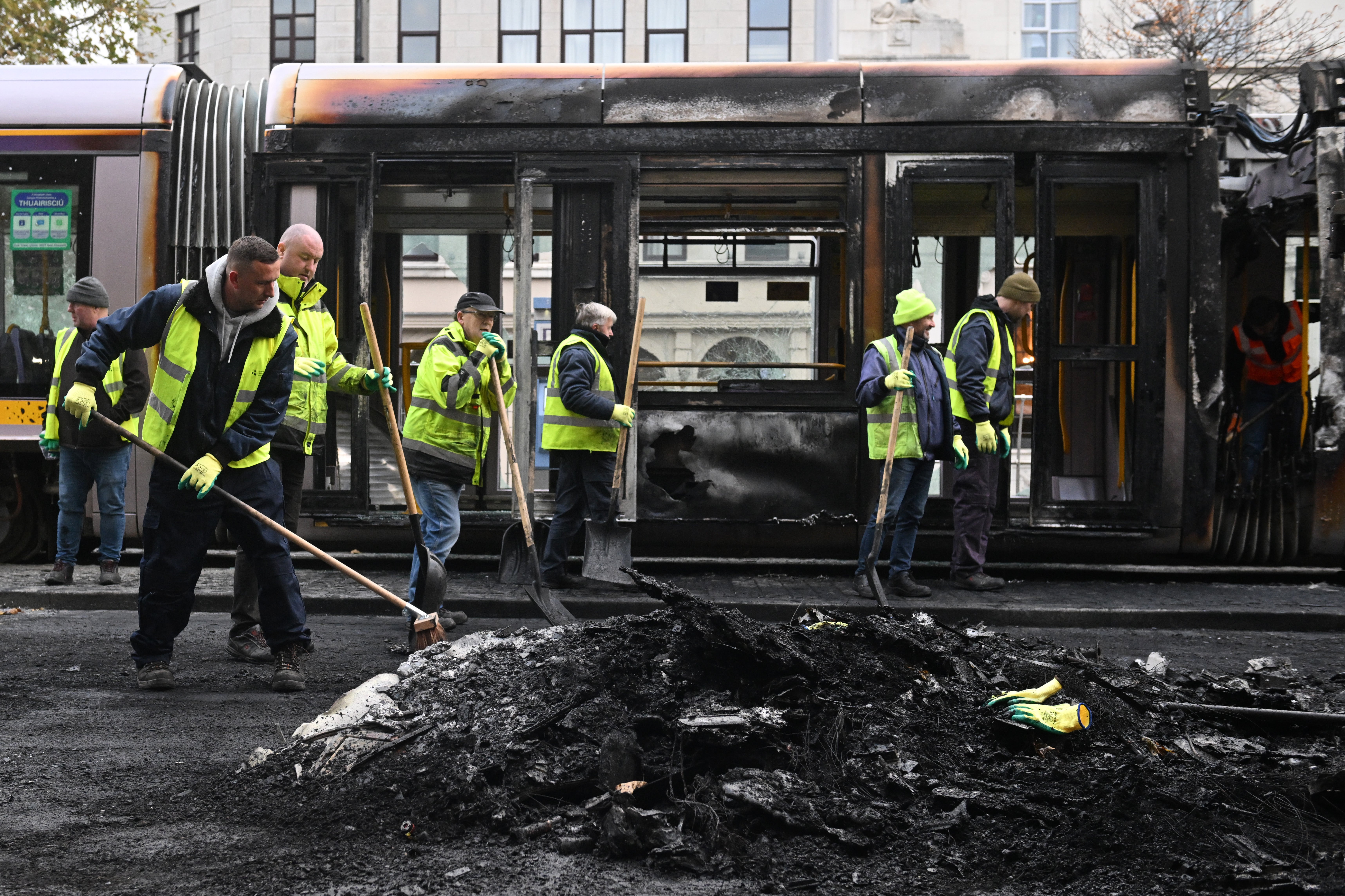 Workers clean up the debris of a burnt train on Friday in the wake of the riots in Dublin, Ireland