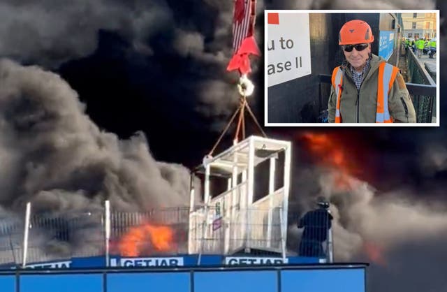 <p>Handout video grab taken with permission from the X feed of Chris Lauder of a workman who was trapped on a roof being lifted to safety by a crane after a fire at a high-rise building in Reading</p>