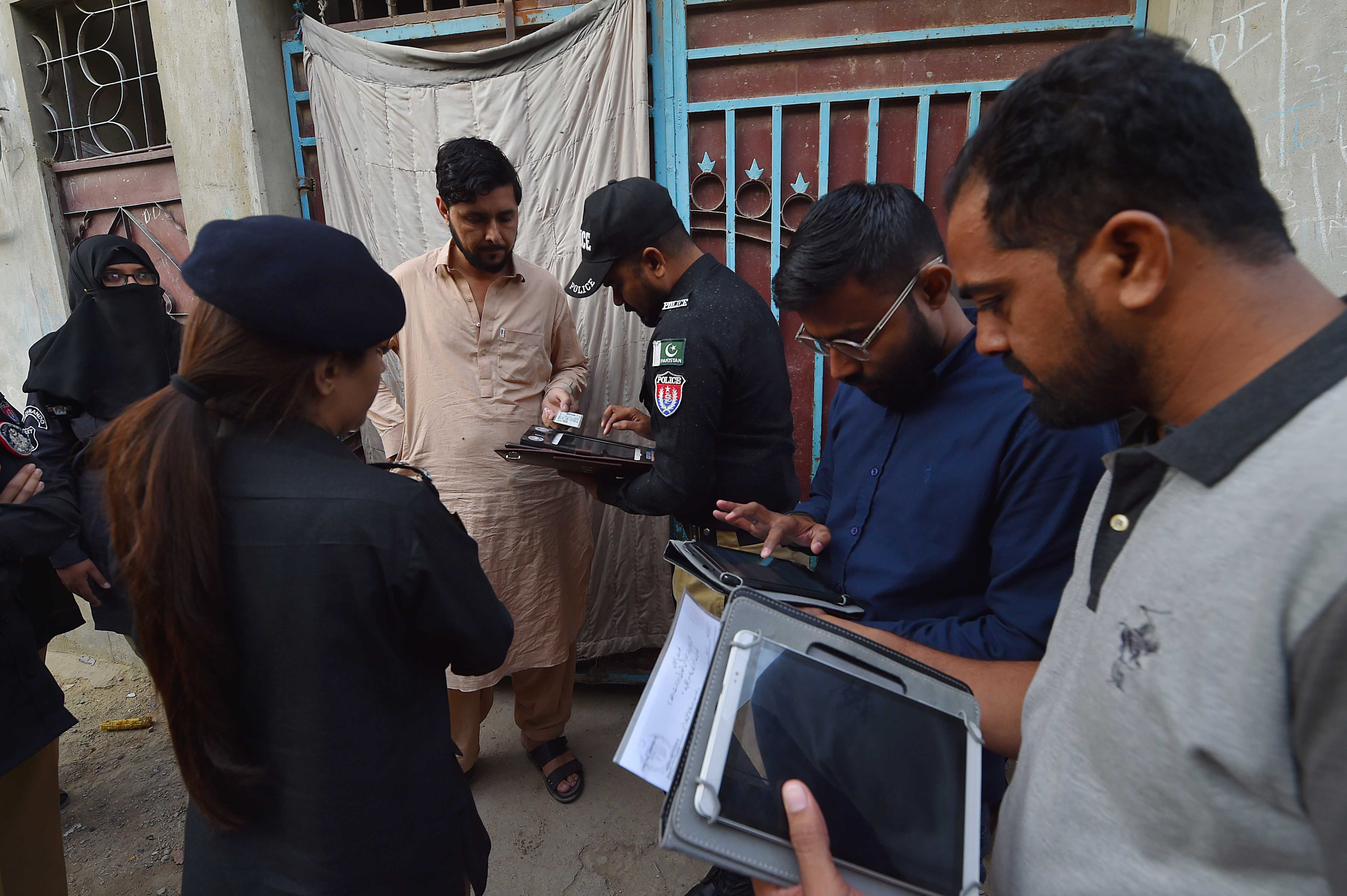 Pakistani police officials check the documents of people during search operation for undocumented immigrants in Karachi
