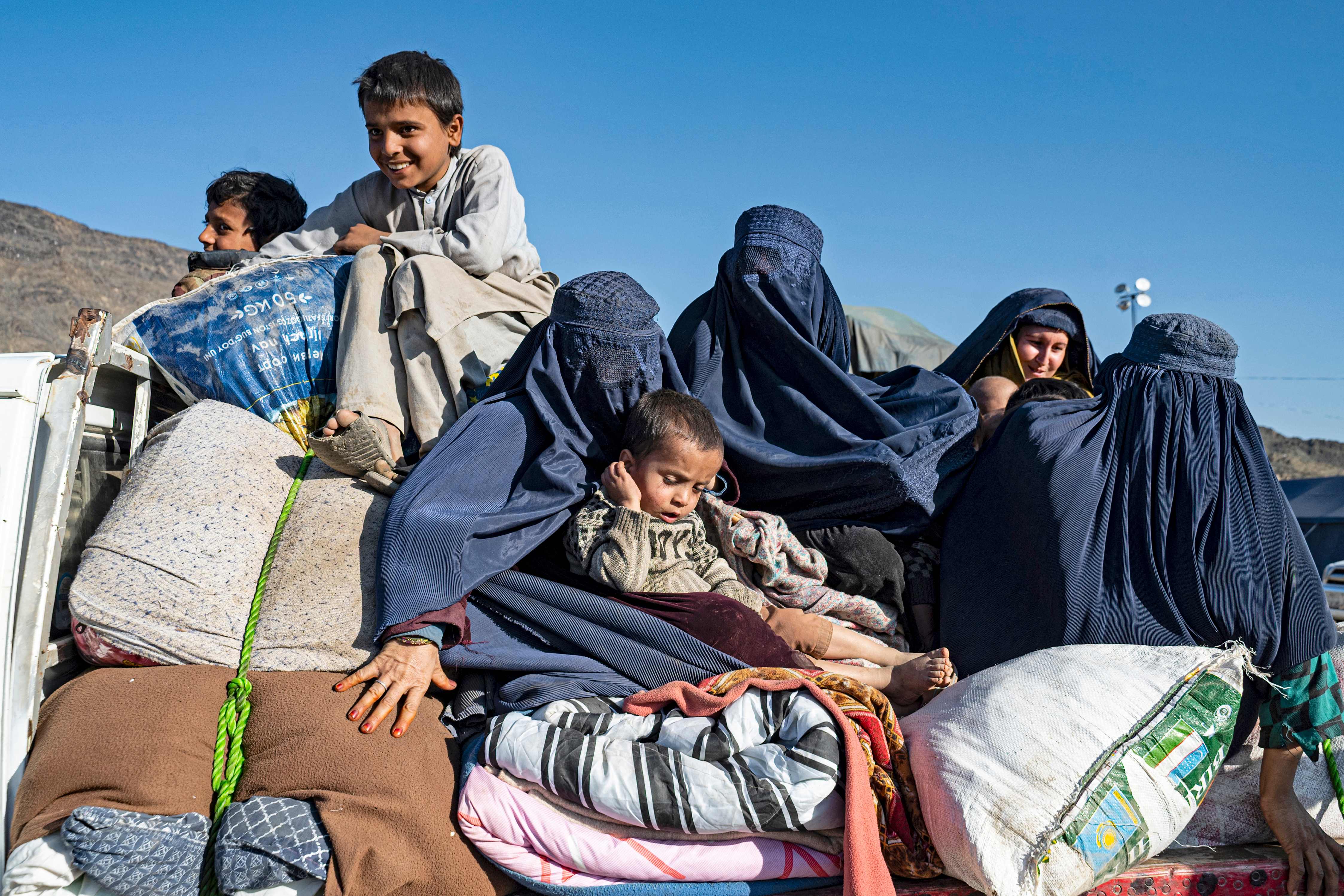 Afghan refugee Shazia (2R), mother to three children, holds an infant while travelling on a truck to Jalalabad from a makeshift camp