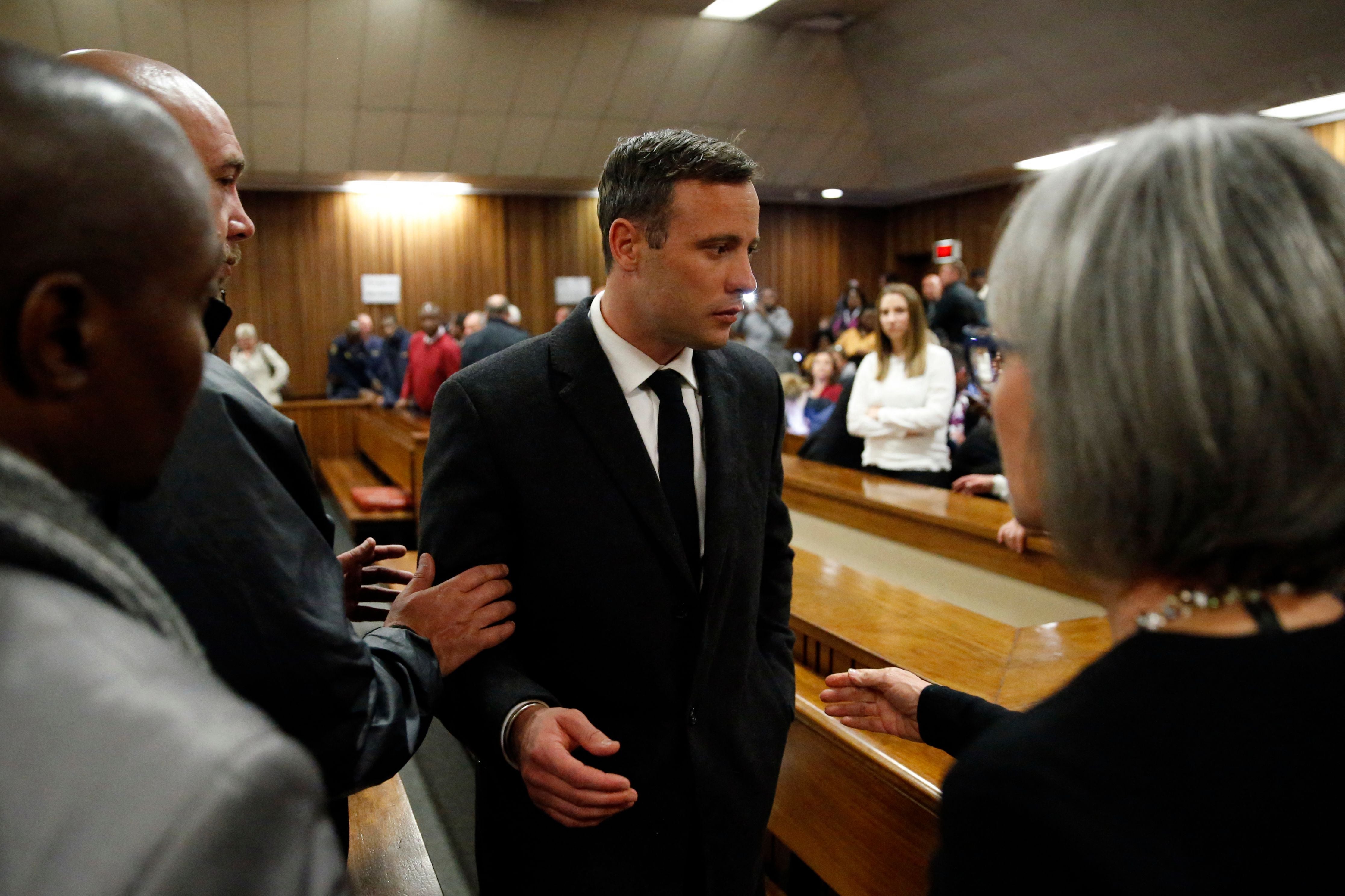 Oscar Pistorius speaks with relatives as he leaves the High Court in Pretoria in 2016
