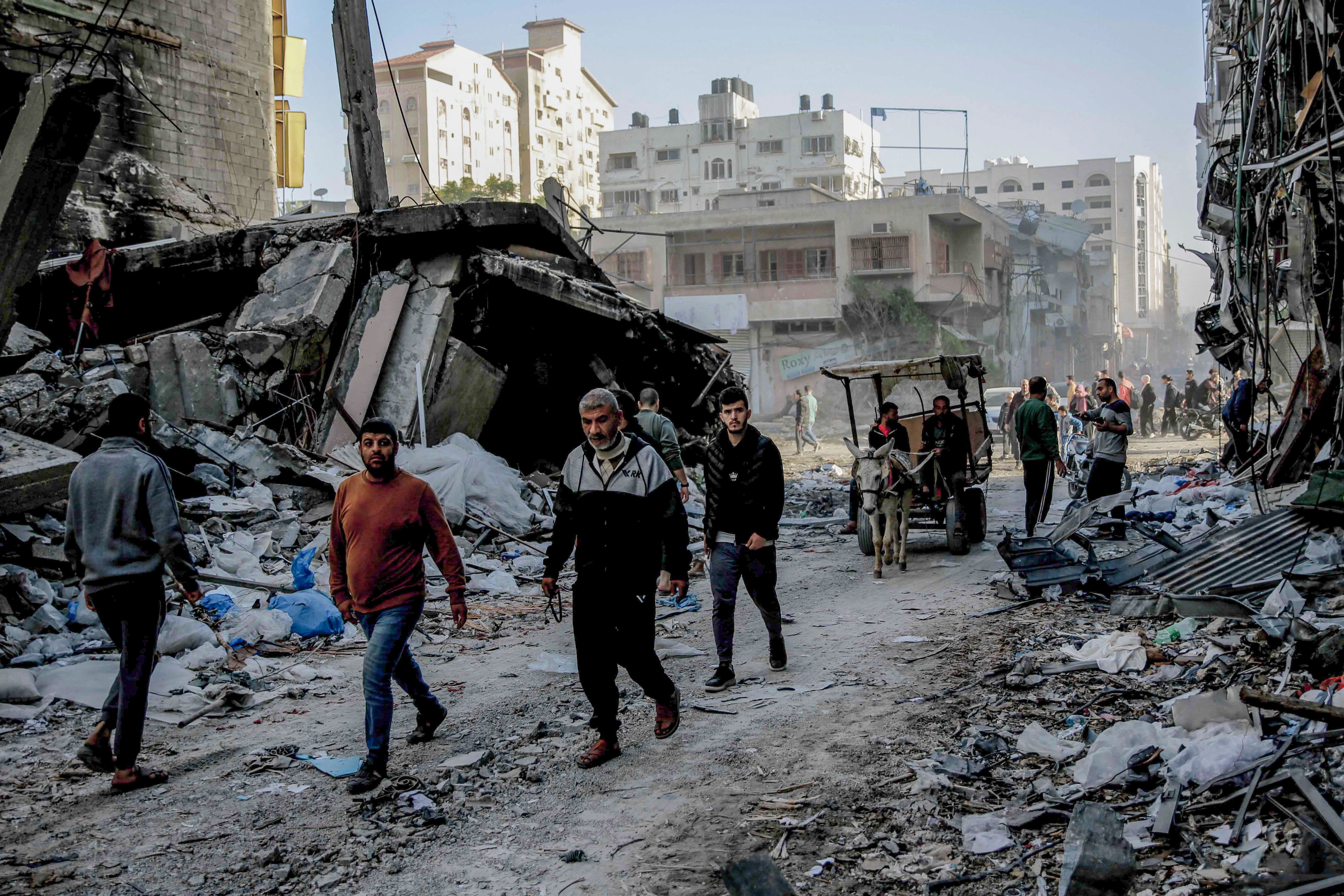 Palestinians walk amid the rubble of destroyed buildings in Gaza City on Friday