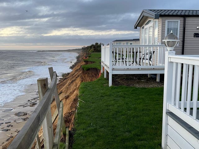 <p>A road has partially collapsed due to high tides and wind leaving caravans exposed</p>
