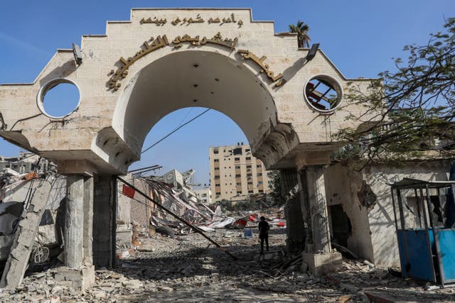 Palestinians walk by a destroyed government building in Gaza City (Mohammed Hajjar/AP)