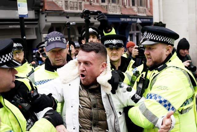 <p>Tommy Robinson is led away by police officers as people take part in a march against antisemitism (Jordan Pettitt/PA)</p>