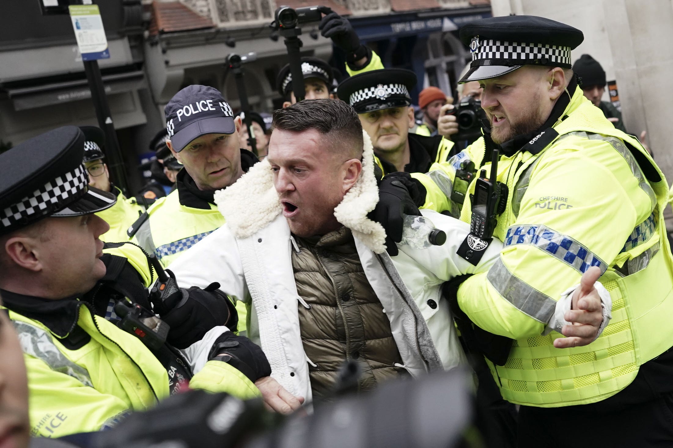 Tommy Robinson is led away by police as people take part in a march against antisemitism