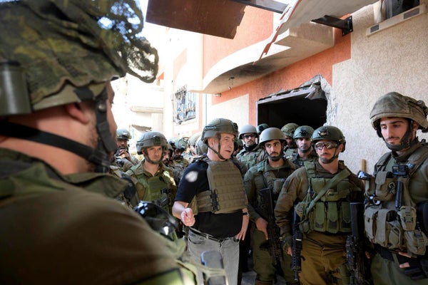 Israel’s prime minister Benjamin Netanyahu, centre, speaks to  soldiers in the Gaza Strip 