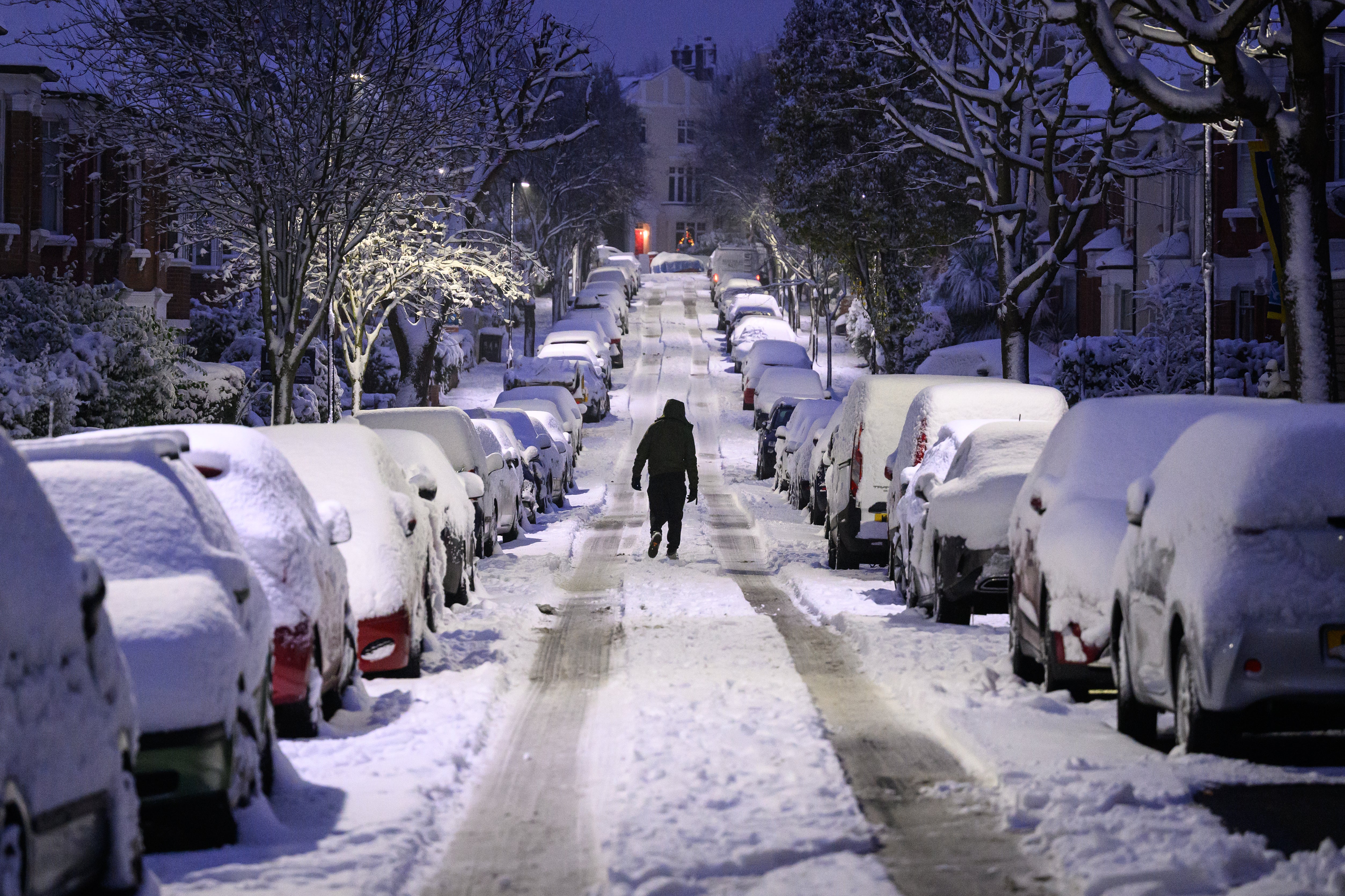A man walks up a snow-covered road in London, England, December 2022