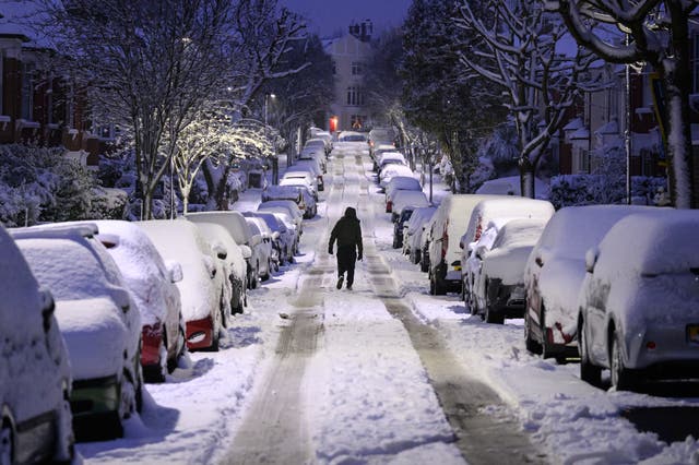 A man walks up a snow-covered road in London, England, December 2022