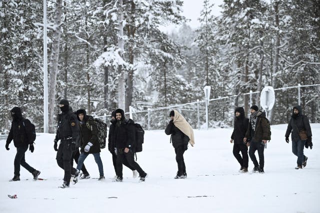 <p>Finnish Border Guards escort migrants arriving at the Raja-Jooseppi international border crossing station between Russia and Finland</p>