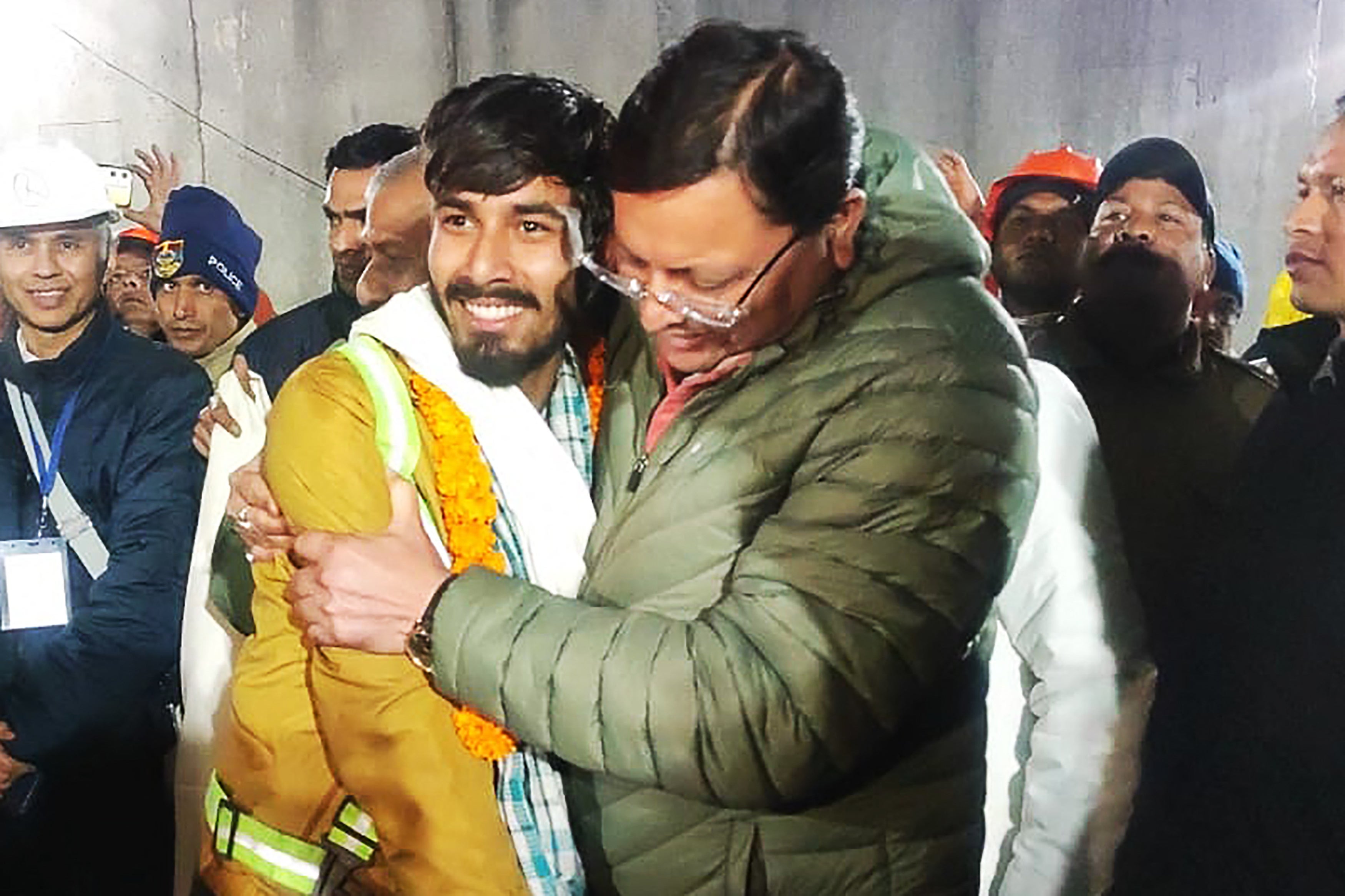 Chief minister of Uttarakhand Pushkar Singh Dhami (R) embracing a contruction worker following his rescue