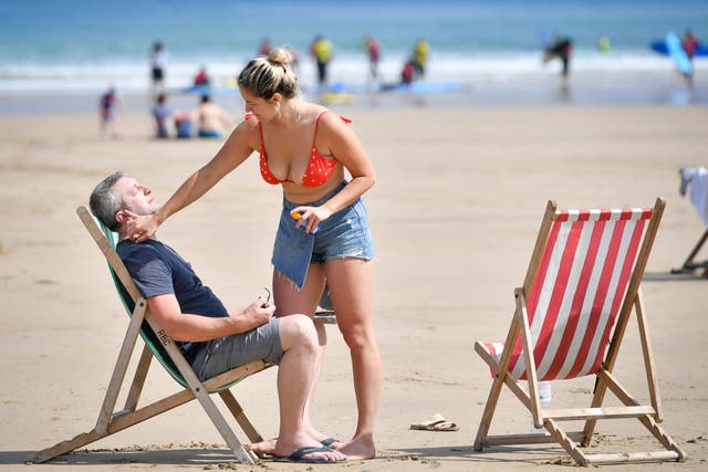 Sunbathers applying sunscreen on Towan beach in Newquay (PA)