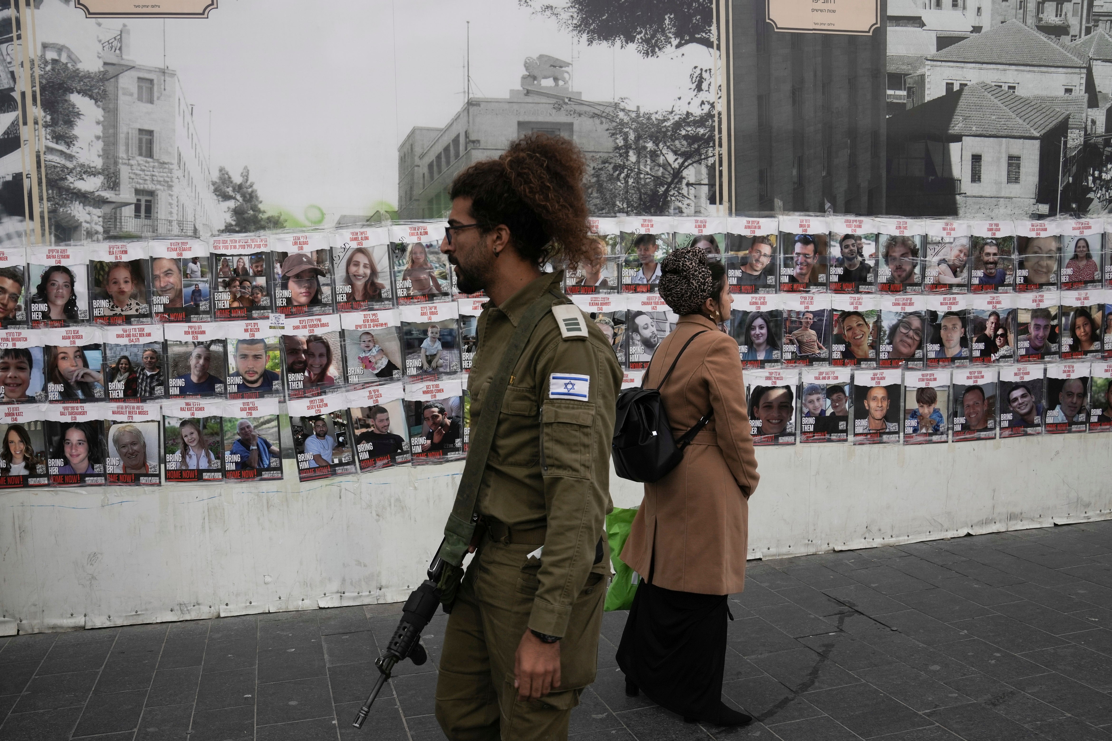 Israelis pass by a wall in Jerusalem with photos of the approximately 240 hostages who were abducted by Hamas on 7 October