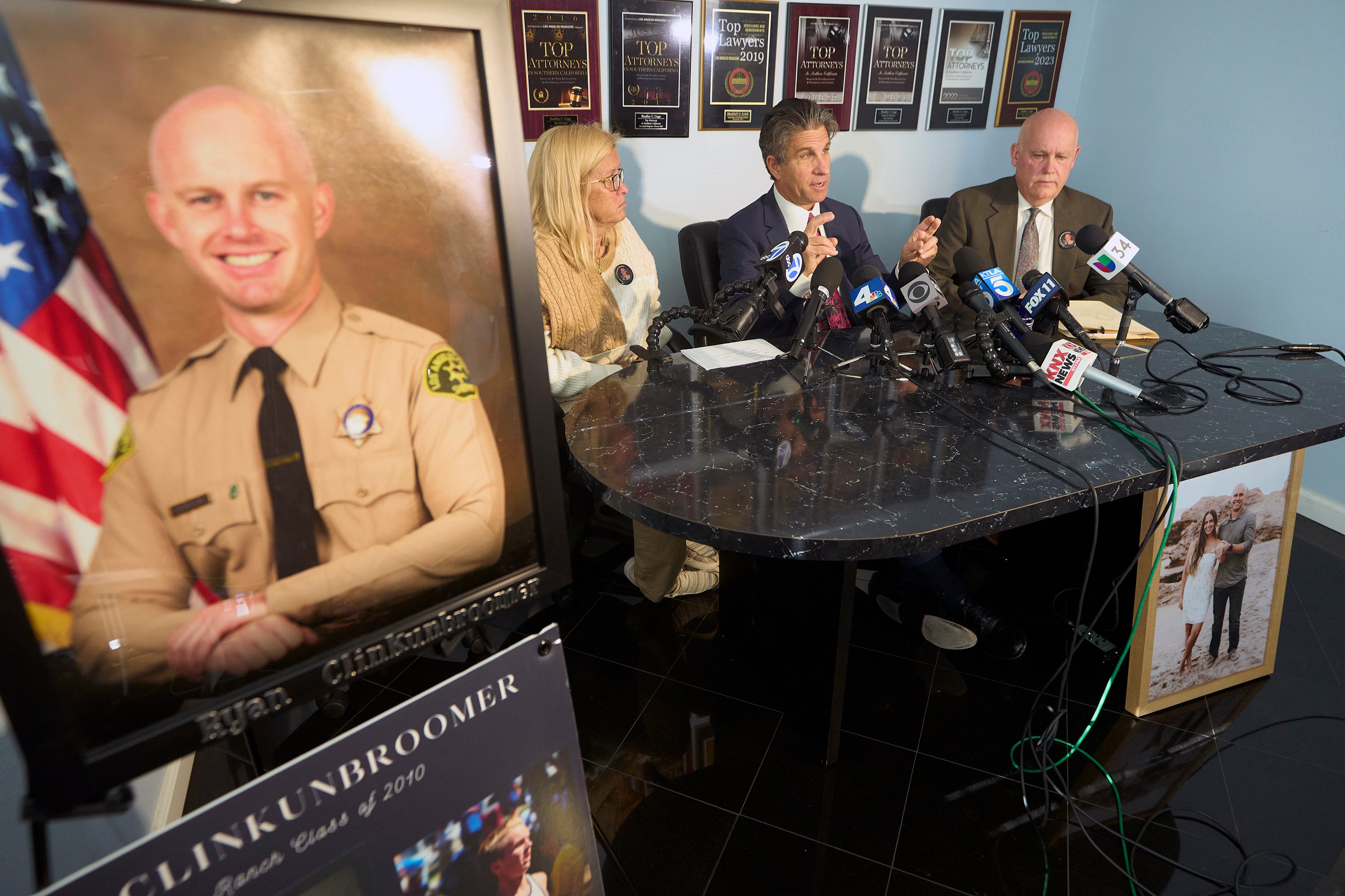 Attorney Bradley Gage, middle, and Kim Clinkunbroomer, left, and Mike Clinkunbroomer, the parents of late Los Angeles Sheriff's Deputy Ryan Clinkunbroomer, pictured left, announce the precursor of a lawsuit against the Sheriff's Department at a news conference in Los Angeles on Tuesday, Nov. 28, 2023.