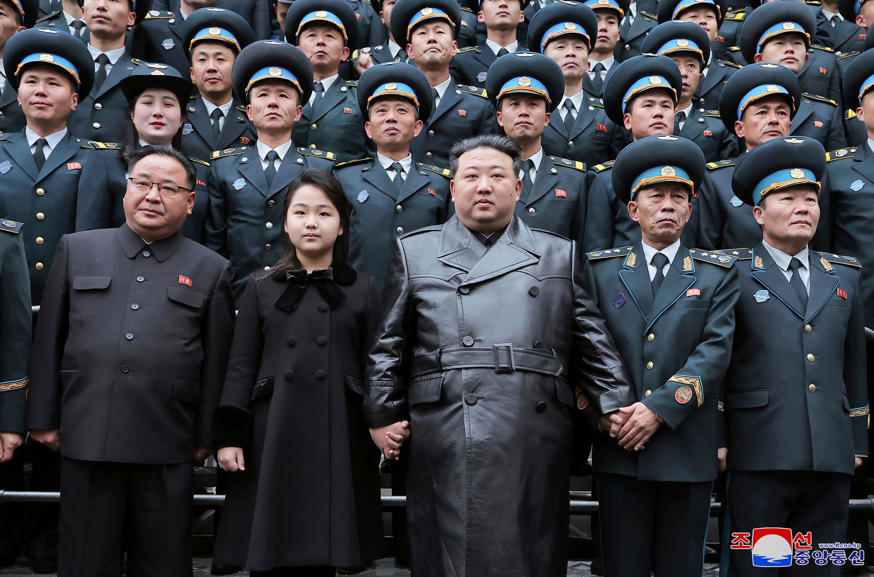 Kim Jong-un and his daughter pose with staff of the National Aerospace Technology Administration (NATA) following the launch