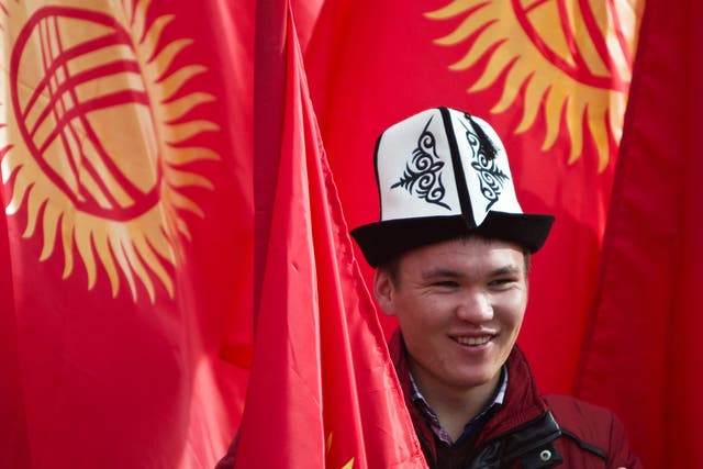<p>A man wearing a Kyrgyz national hat poses with national flags before a rally marking the Day of Flag and the Day of Kolpak in Bishkek, Kyrgyzstan</p>