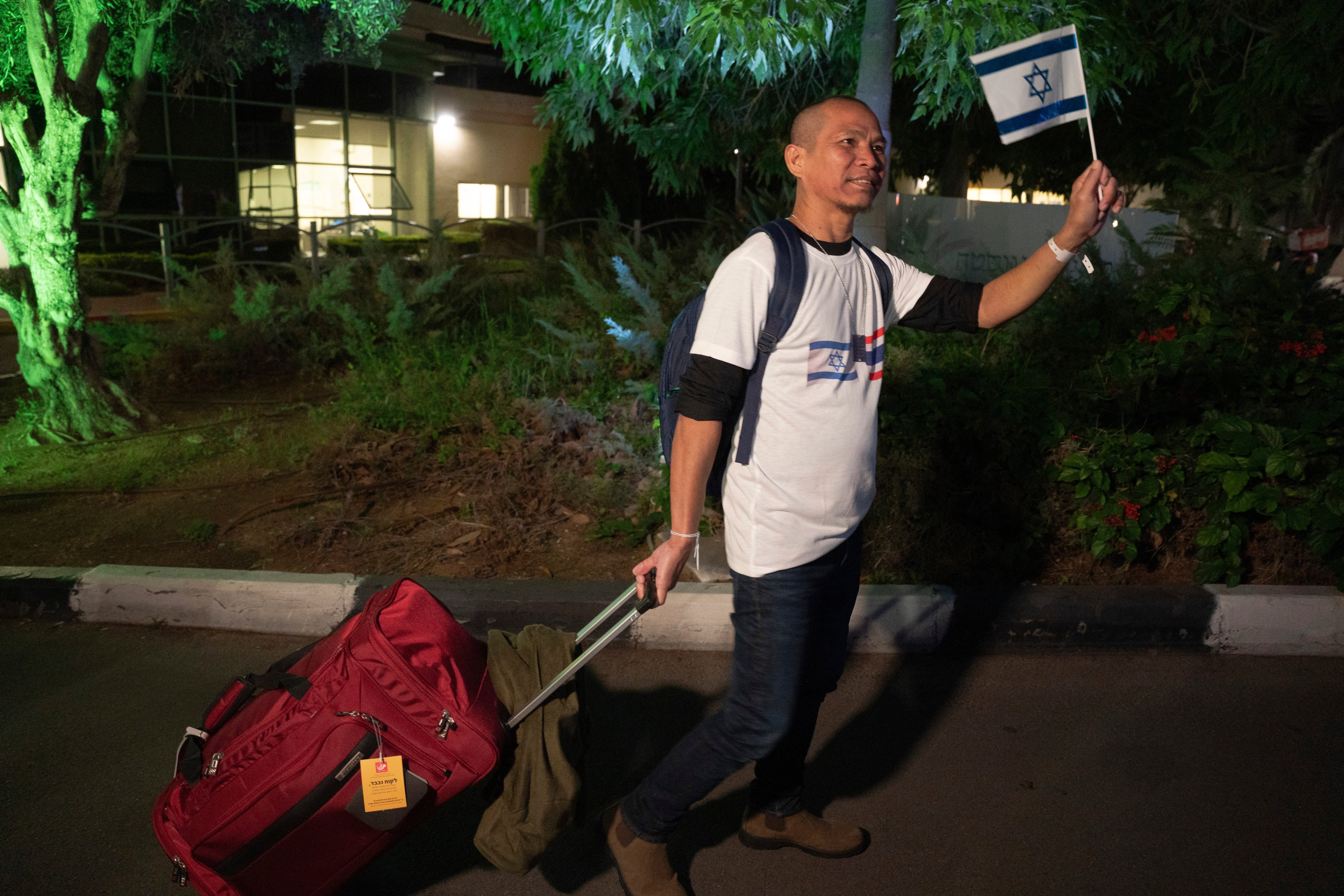 A Thai national waves an Israeli flag while walking to a bus leaving the Shamir Hospital in Ramle, Israel, Wednesday, 29 November 2023, on his way back to Thailand, after being released from Hamas custody. International mediators on Wednesday worked to extend the truce in Gaza, encouraging Hamas militants to keep freeing hostages in exchange for the release of Palestinian prisoners and further relief from Israel's air and ground offensive