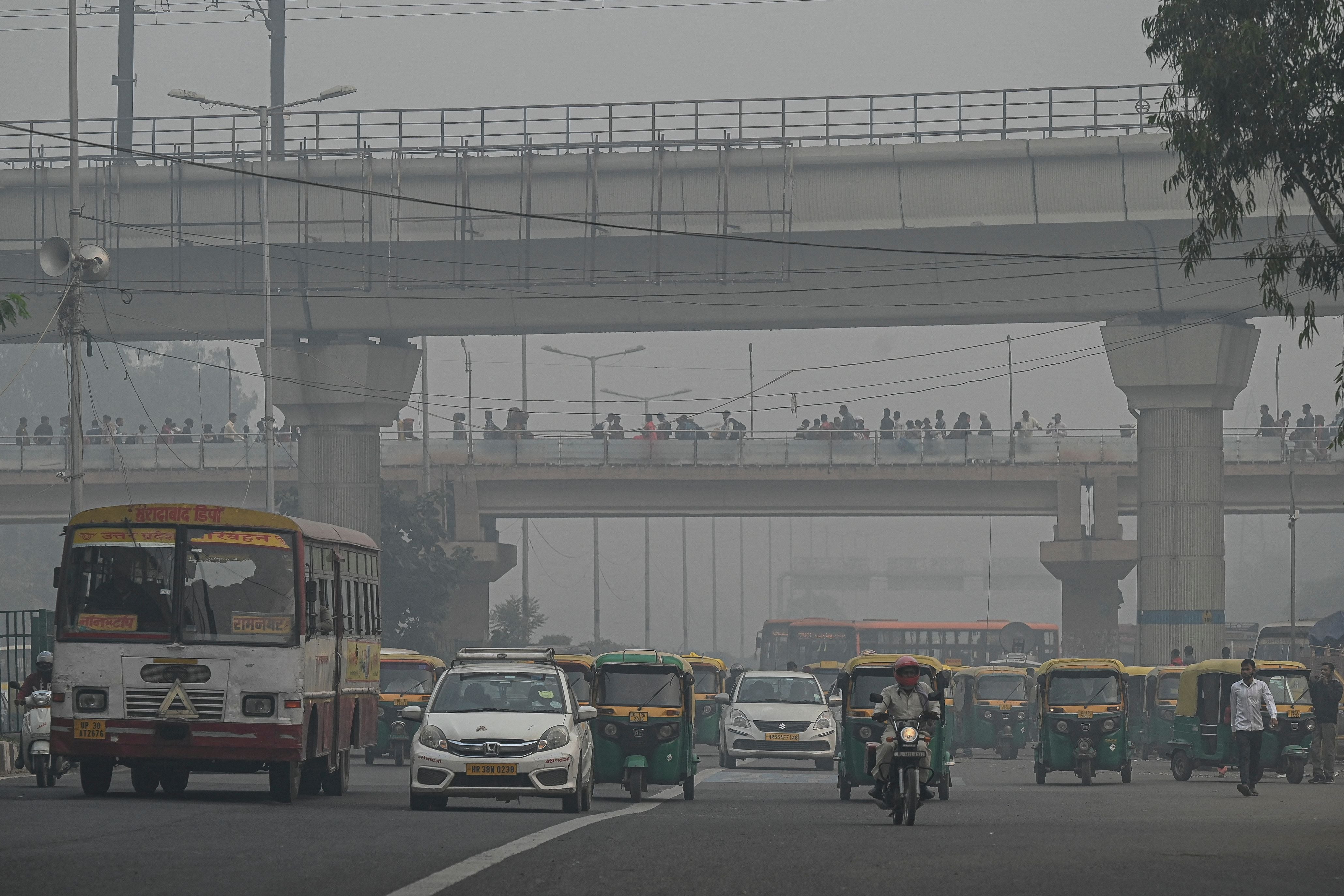 Commuters make their way along a street amid smoggy conditions in New Delhi